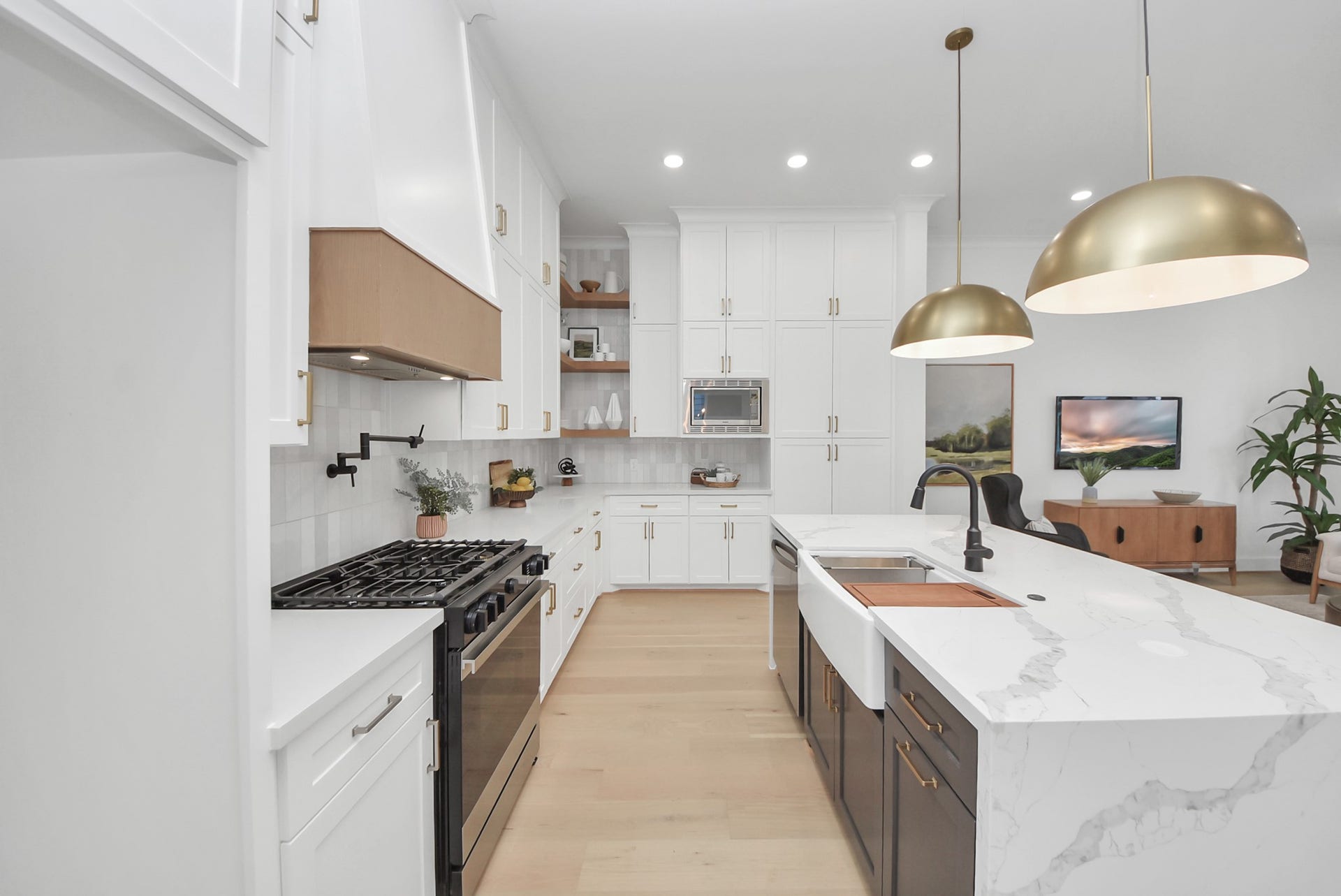 927 Fisher Street, #B, Houston, TX 77018 This modern kitchen invites you to cook and entertain with sleek white cabinetry, a spacious marble island, stainless steel appliances, and brass pendant lights. The open layout flows into the living area, creating a bright and functional space for gatherings.
