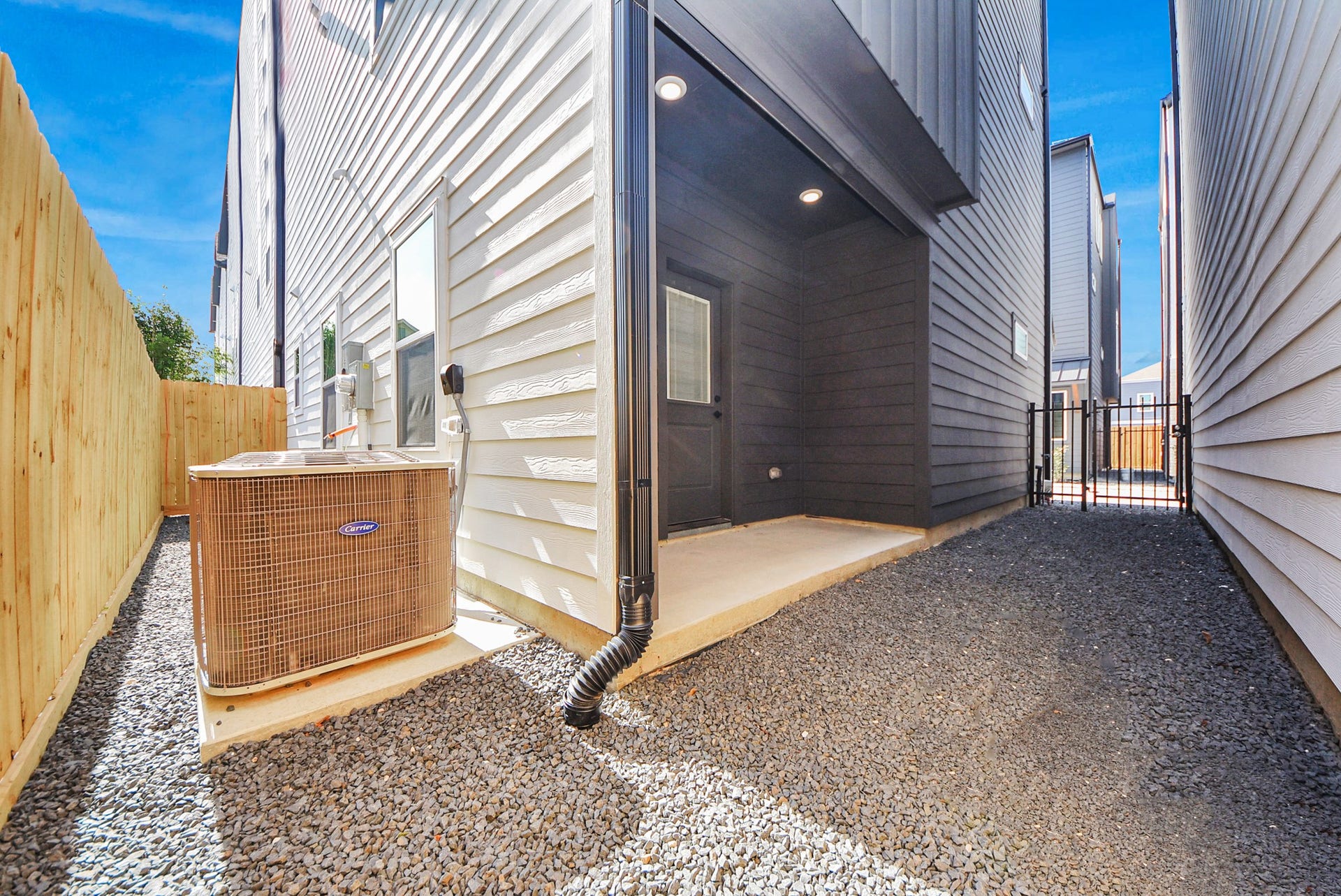927 Fisher Street, #B, Houston, TX 77018 This functional side yard features gravel ground cover, a wooden fence, and an outdoor air conditioning unit. A gated entry provides secure access, making the space practical and well-maintained for utility needs.