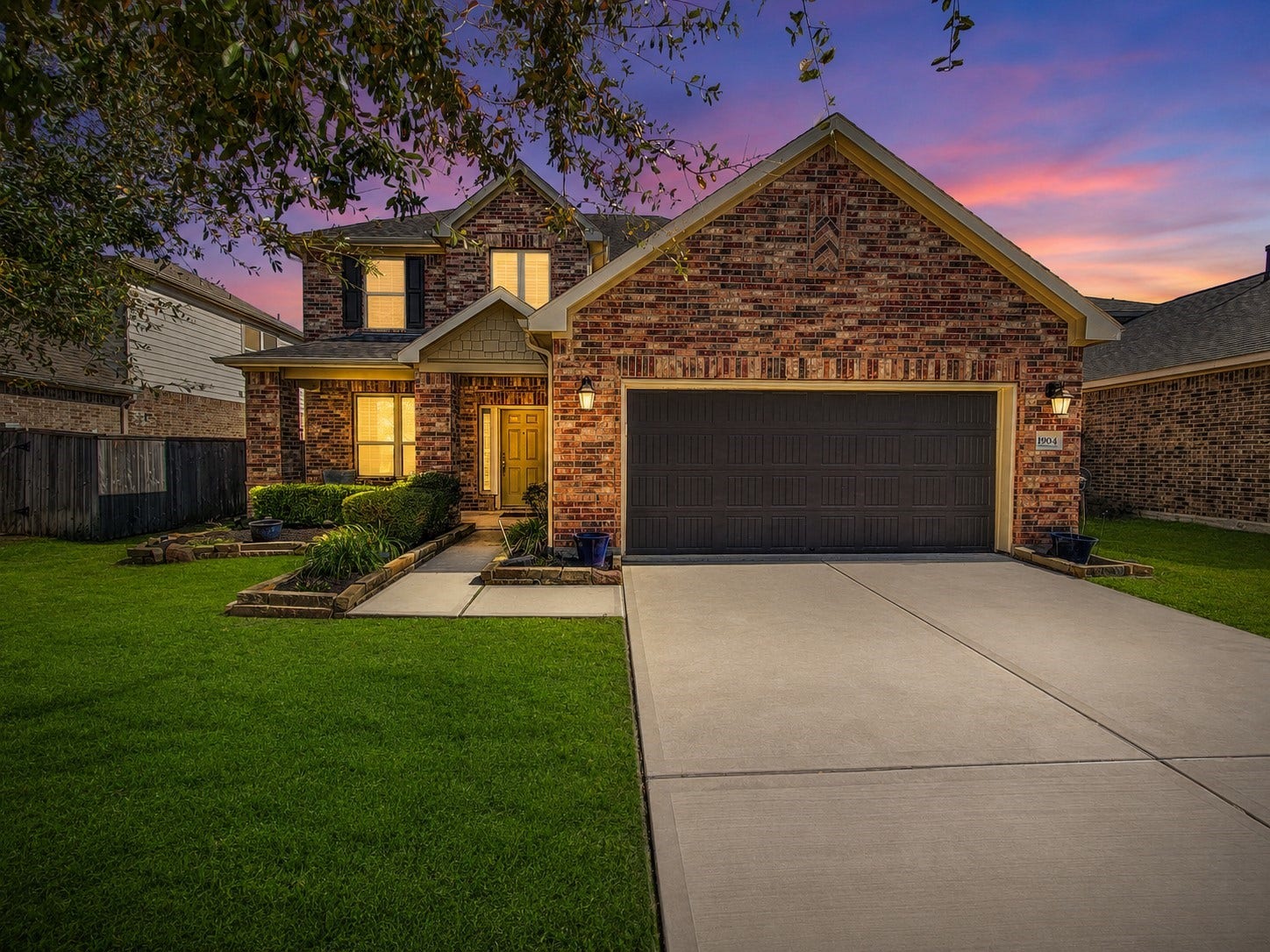 1904 Emerald Breeze Court, Pearland, TX 77089 Charming two-story brick house with a well-maintained front yard and a spacious driveway leading to a two-car garage. The home features a welcoming front entrance with landscaping and mature trees providing shade.