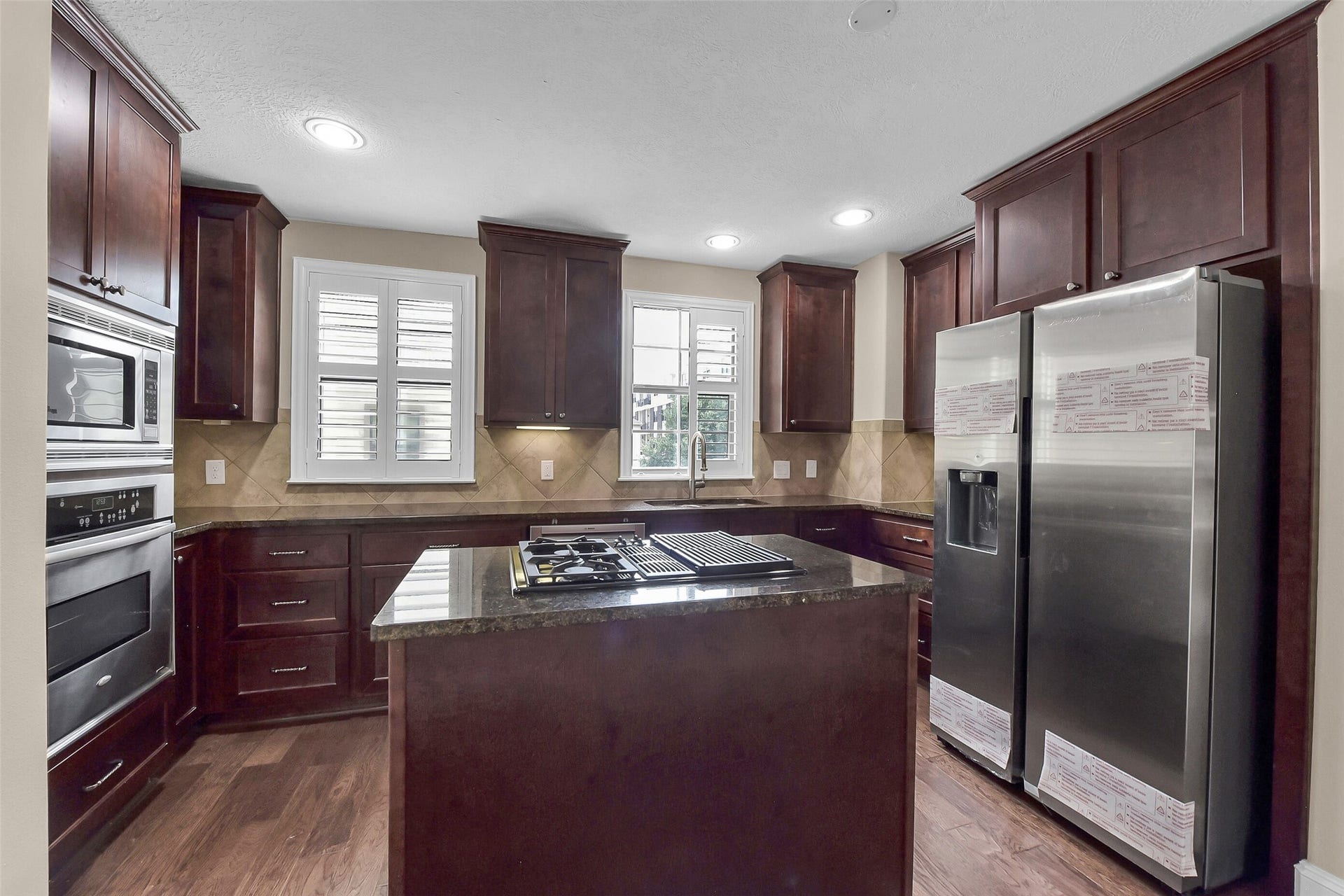 905 Garden Oaks Trace, Houston, TX 77018 The island kitchen features a gas cooktop, stainless steel appliances, under cabinet lighting, granite counter tops, tile backsplash and upper and lower cabinets.