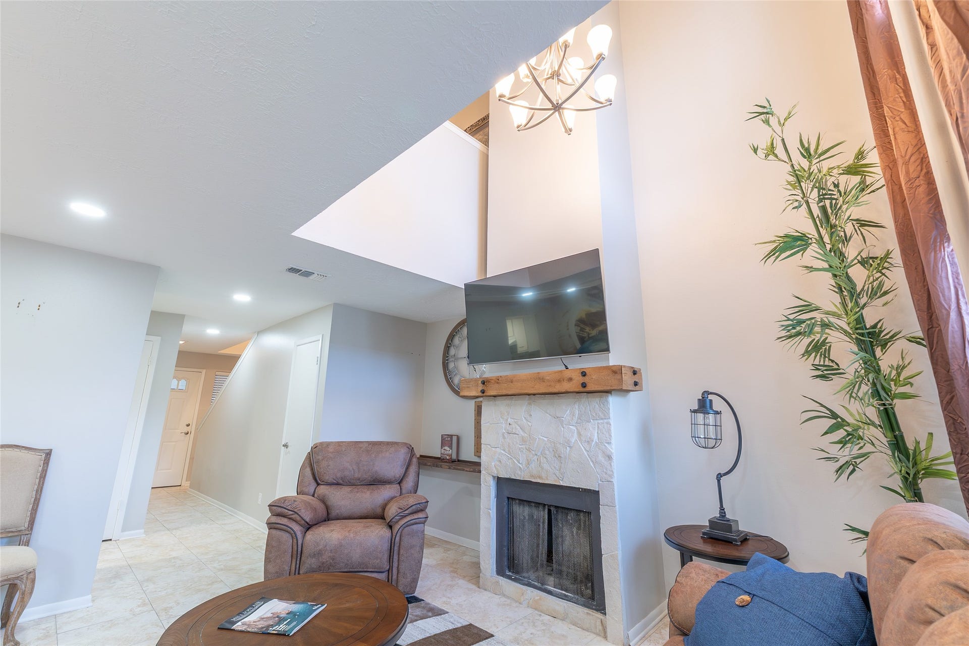 looking towards the back of the townhome. closet and stairs middle left, cubby space, fireplace, TV and chandelier on right