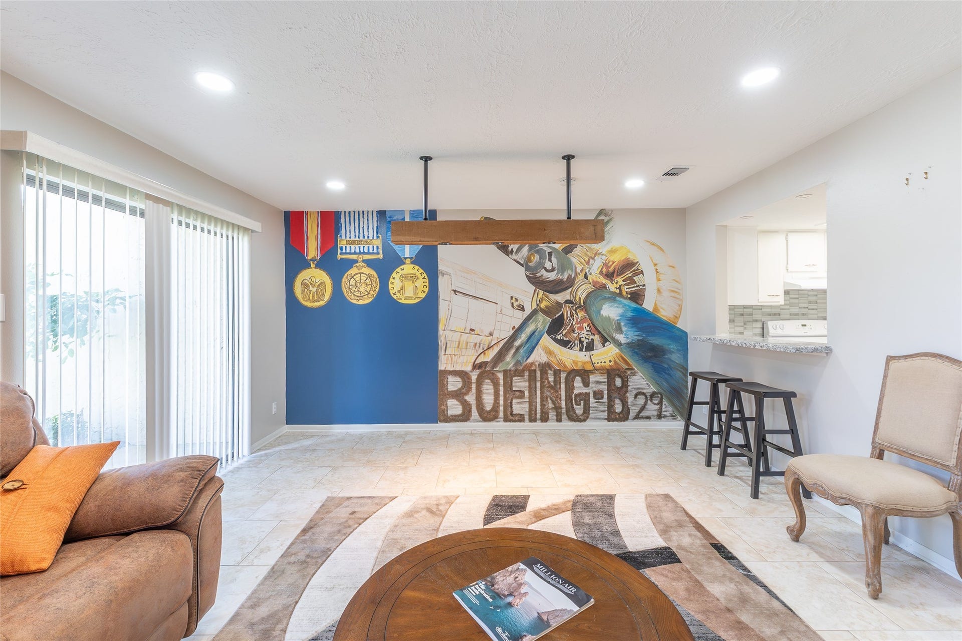 mural, front door on the left, breakfast bar and kitchen on the right, family room on foreground.