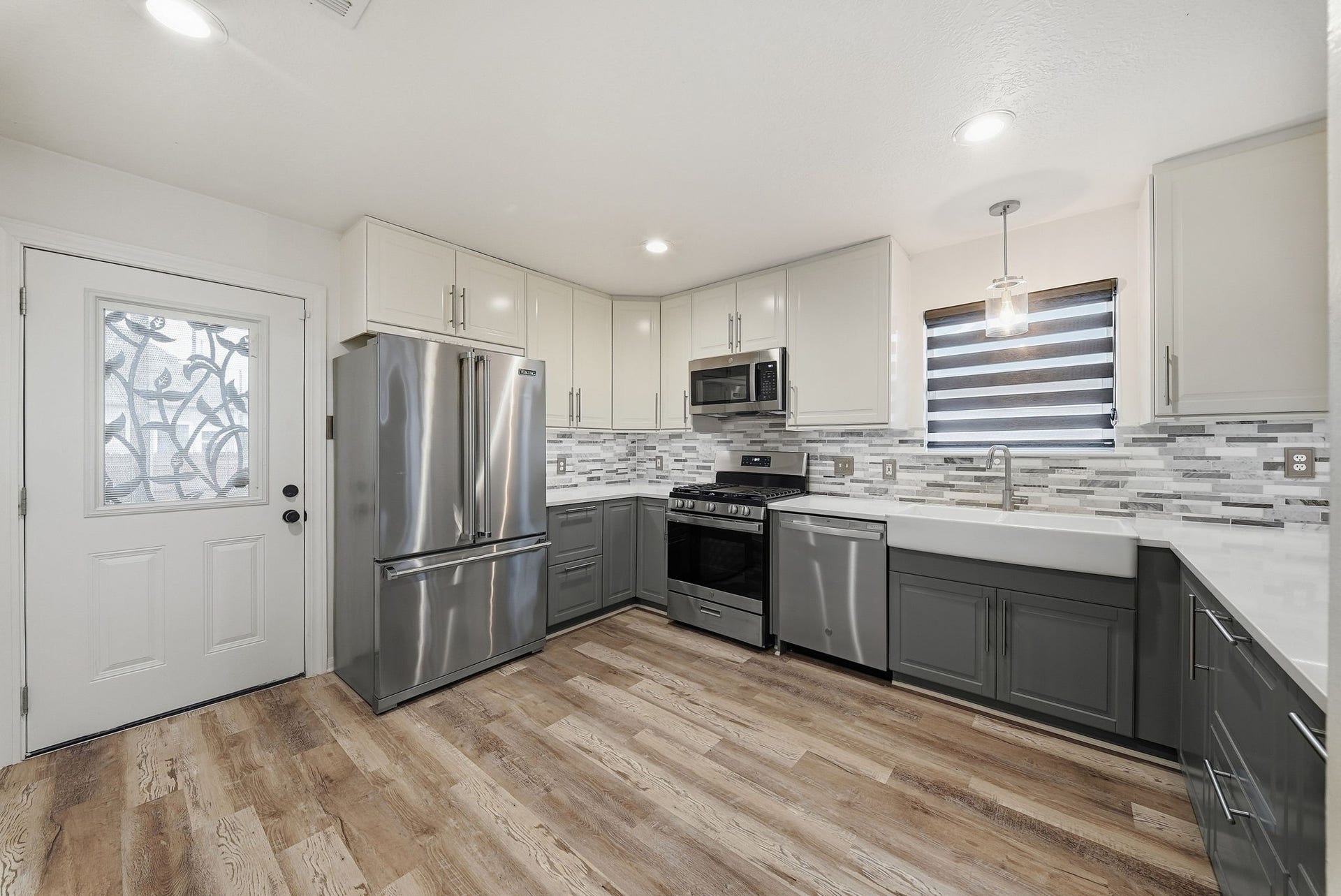 1917 Chapman Street, Houston, TX 77009 Bright, modern kitchen featuring stainless steel appliances, granite countertops, and a farmhouse-style sink.