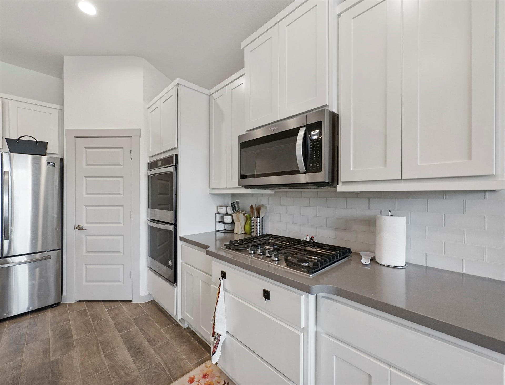28226 Hazel Trail, Katy, TX 77494 A gas cooktop sits beneath a built-in microwave, framed by a white subway tile backsplash and generous cabinet storage.