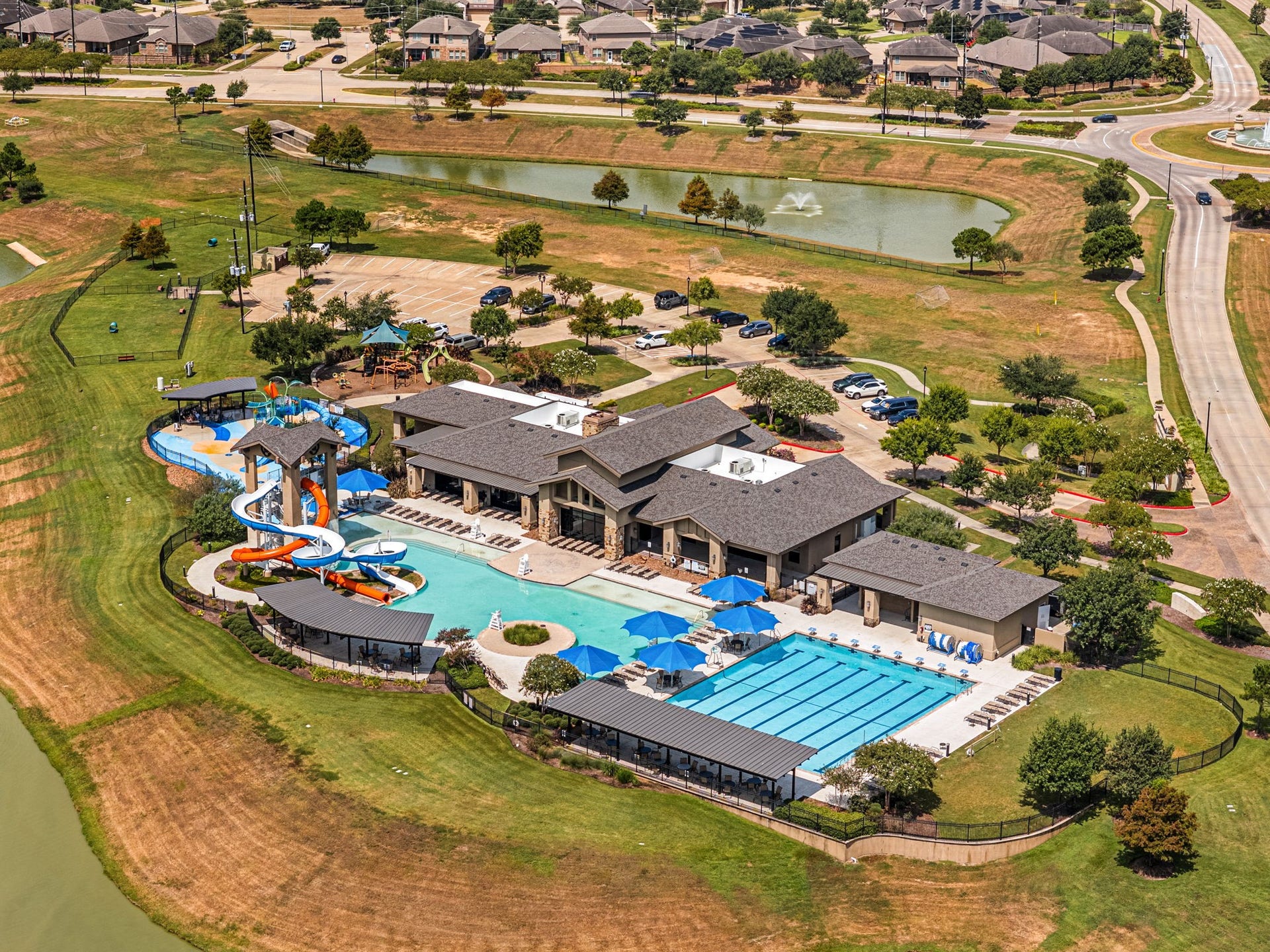 28226 Hazel Trail, Katy, TX 77494 Tamarrons resort-style amenity complex features a resort pool with water slides and splash features, a dedicated lap pool, shaded seating areas, and an adjacent playground, offering plenty of ways to swim, play, and spend time outdoors.