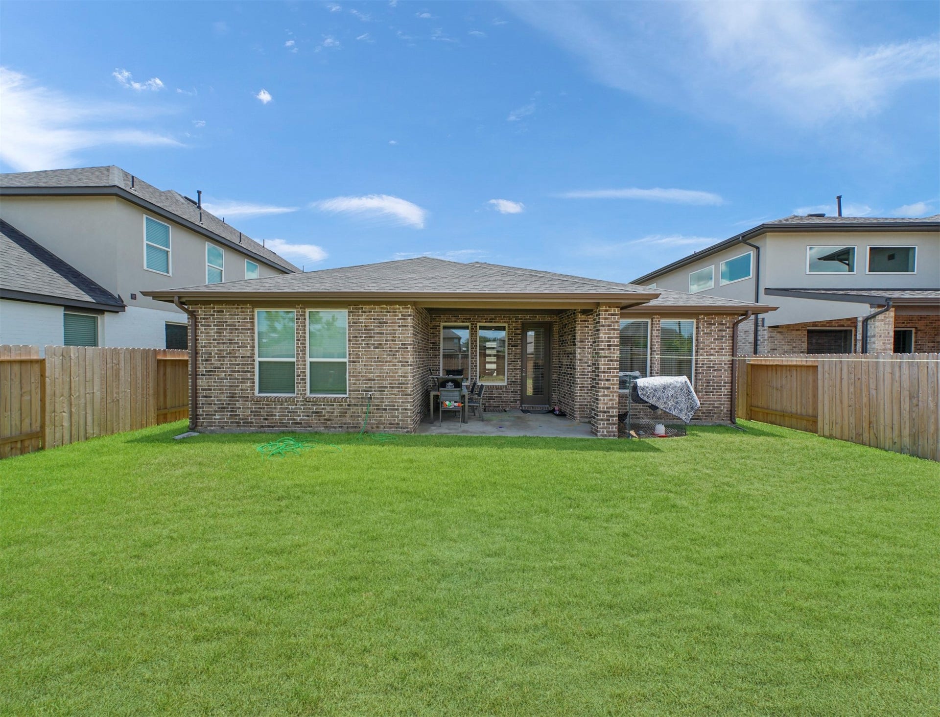 28226 Hazel Trail, Katy, TX 77494 Step outside to a covered patio framed by brick columns, opening onto a fully fenced backyard with a wide, open lawn for outdoor dining and relaxing.