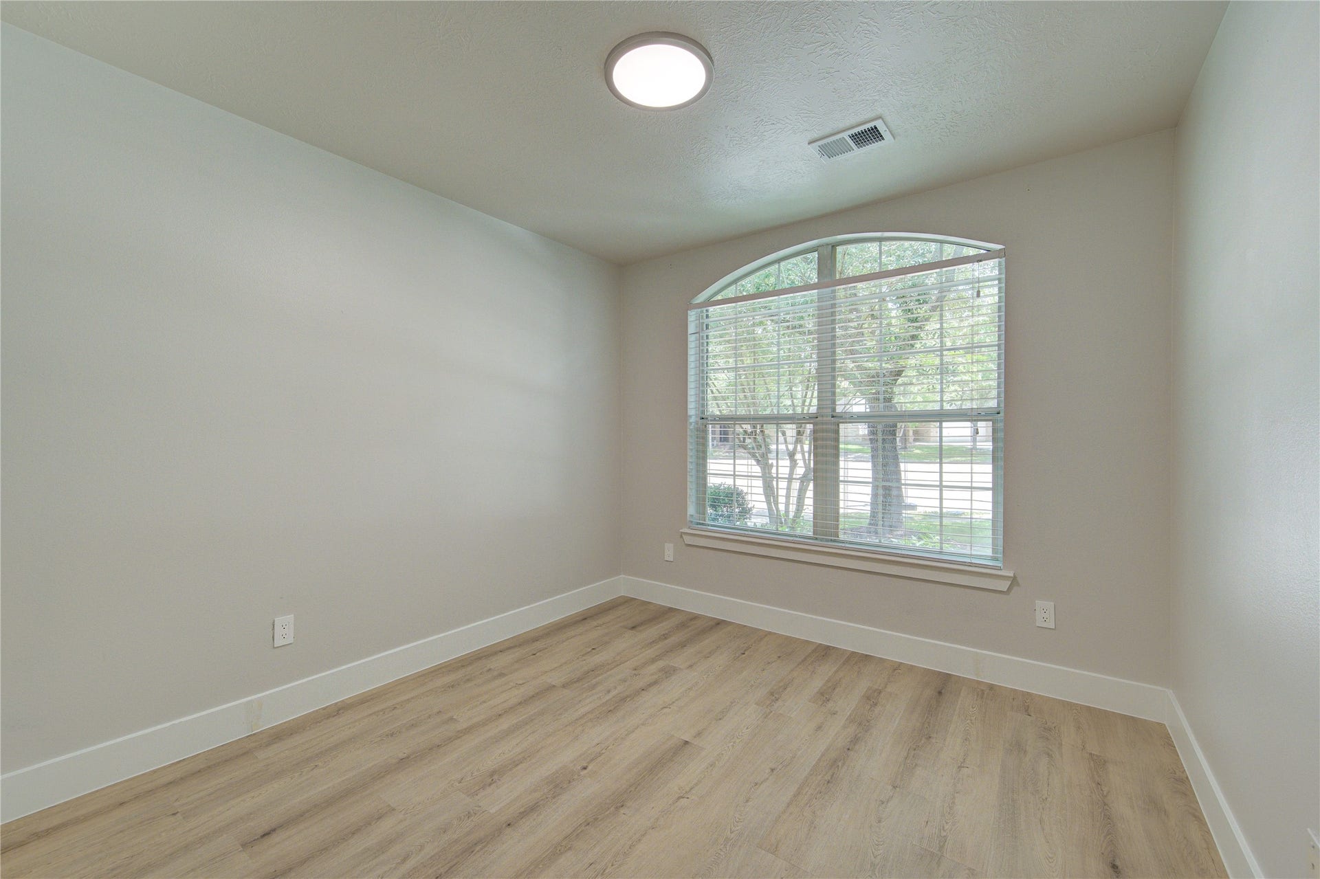 4931 Lake Catherine Court, Richmond, TX 77407 Large front-facing bedroom filled with natural light from an oversized arched window creating a bright and inviting space