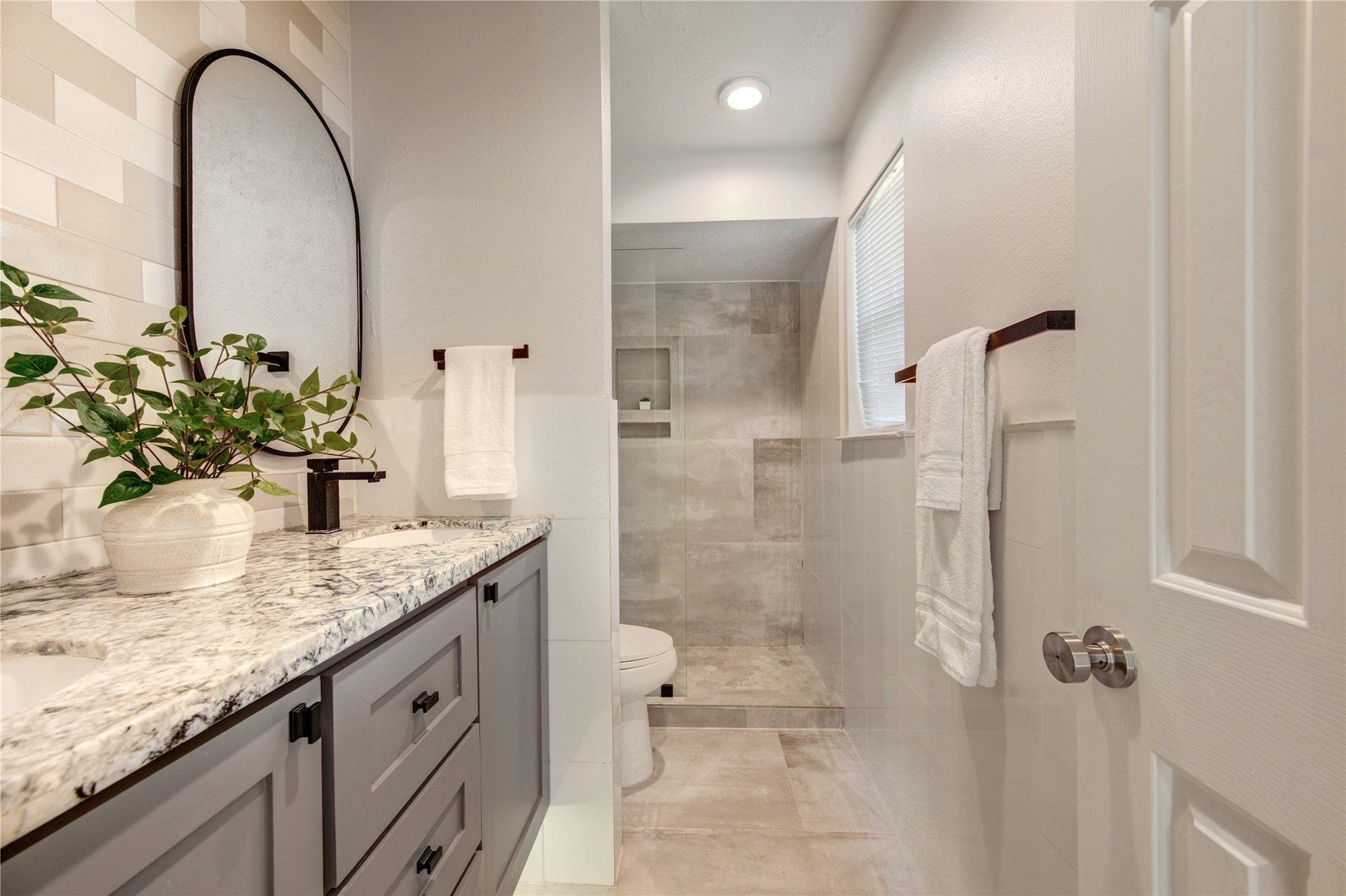 4931 Lake Catherine Court, Richmond, TX 77407 stylish bathroom featuring a granite-topped vanity, contemporary black fixtures and a spacious walk-in shower with elegant tilework