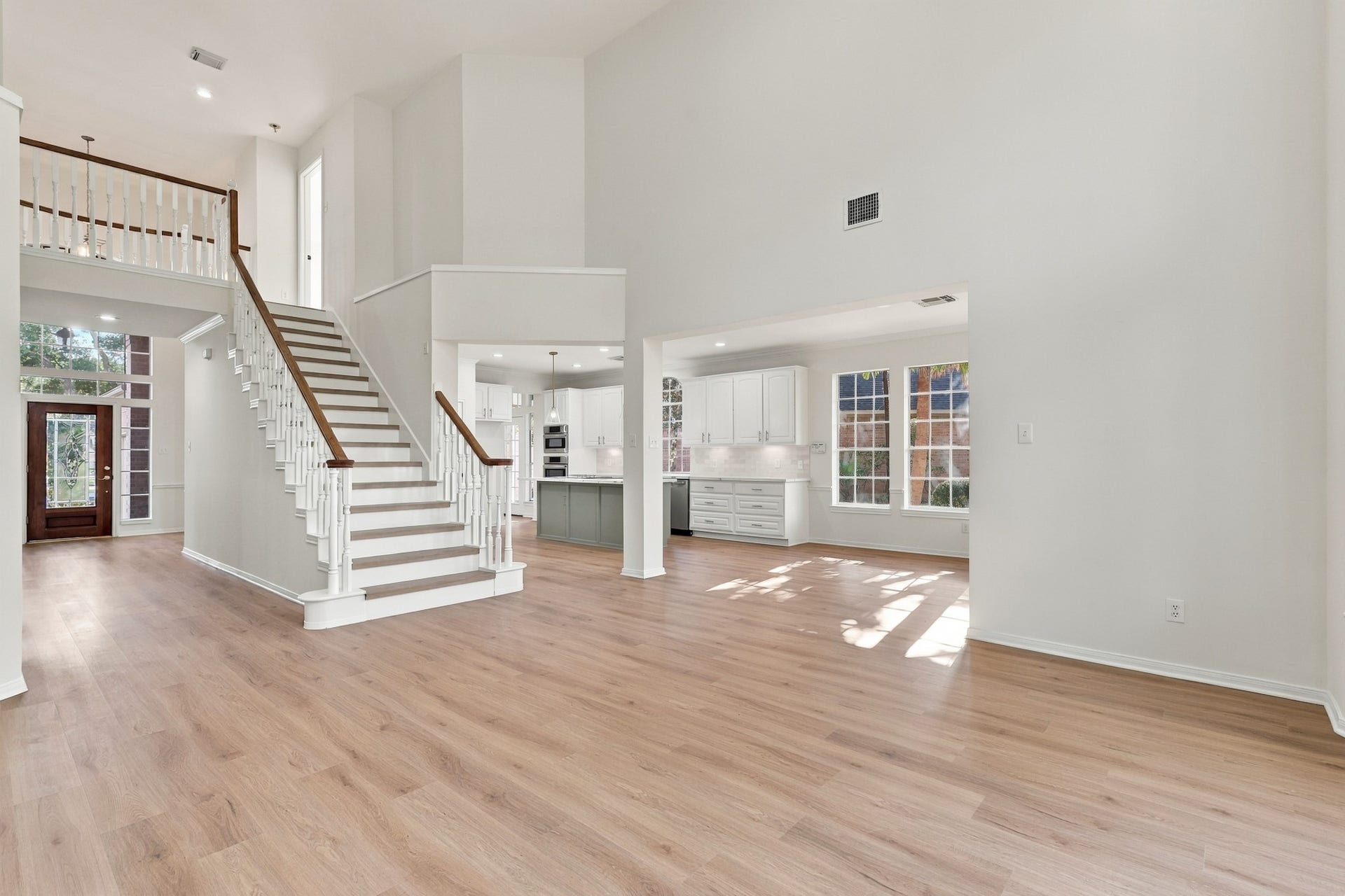1931 Auburn Trail, Sugar Land, TX 77479 Spacious open-concept living area with high ceilings, featuring a grand staircase and abundant natural light from large windows, seamlessly flowing into a modern kitchen with sleek cabinetry.