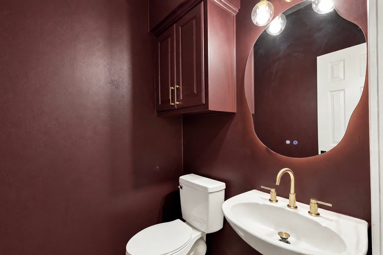 1931 Auburn Trail, Sugar Land, TX 77479 Chic powder room featuring rich burgundy walls, a modern round mirror, gold fixtures, and sleek cabinetry for a touch of luxury.