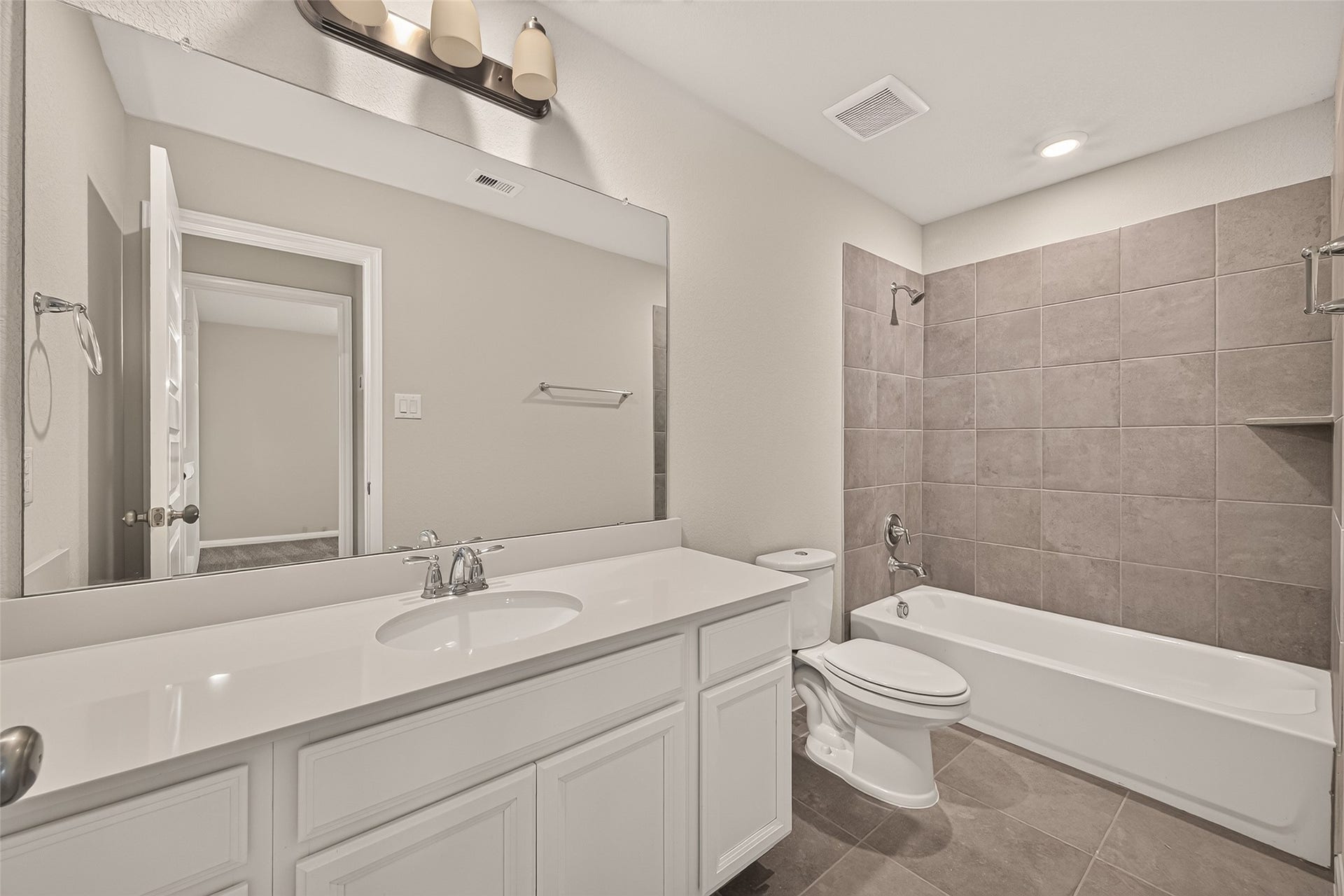 The secondary bathroom offers a modern bathroom featuring a sleek vanity, large mirror, and a shower-tub combo with elegant tilework.
