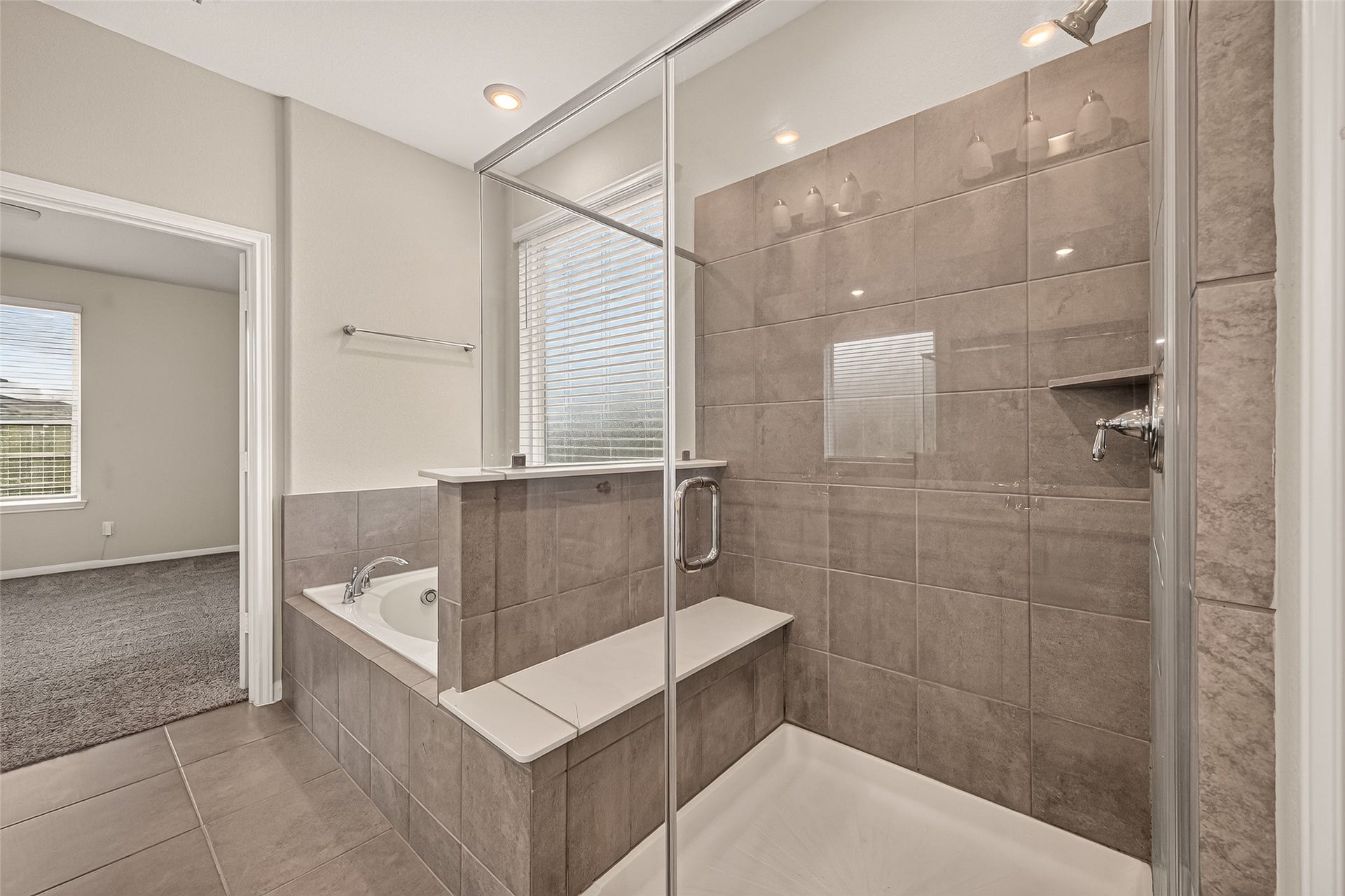 Spacious bathroom featuring a sleek glass-enclosed shower with modern tilework and an adjacent soaking tub, offering a serene retreat.