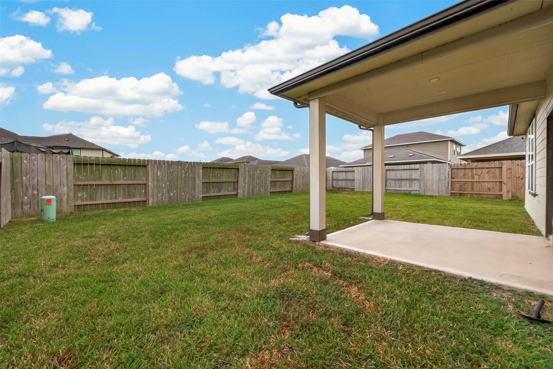 Spacious backyard with a covered patio, perfect for outdoor relaxation and entertaining, all enclosed by a wooden privacy fence.
