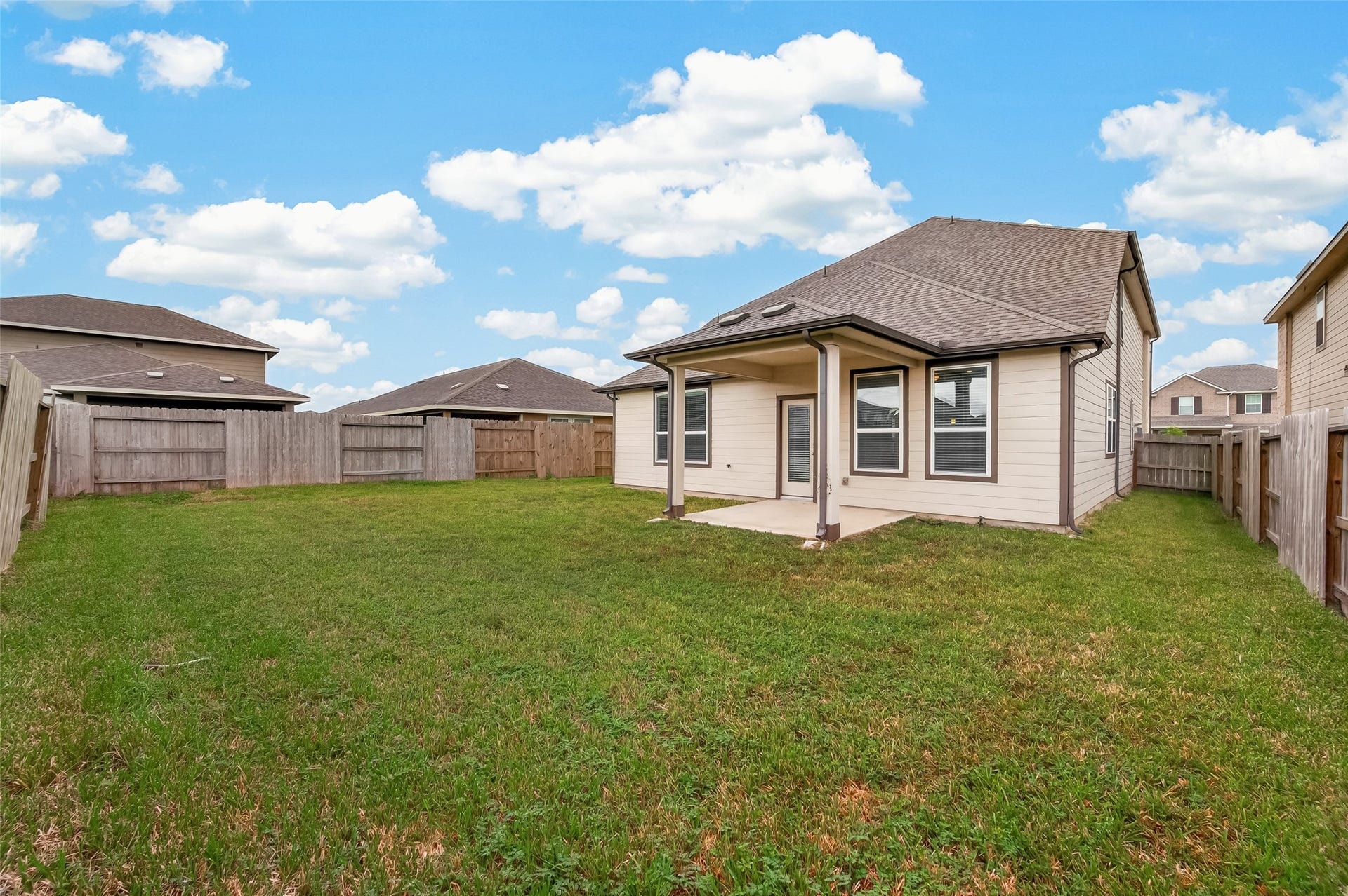 Charming backyard with a spacious lawn and a covered patio, perfect for outdoor gatherings and relaxation.