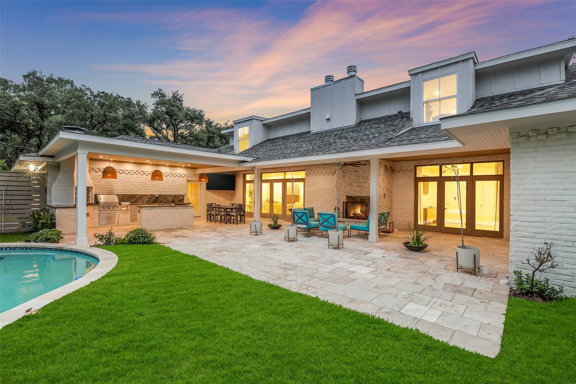 9411 Millbury Drive, Houston, TX 77096 A private, beautifully landscaped backyard featuring a sparkling pool, lush lawn, and covered patio the perfect setting for relaxing or entertaining outdoors. The home's modern exterior and mature trees complete this serene retreat.