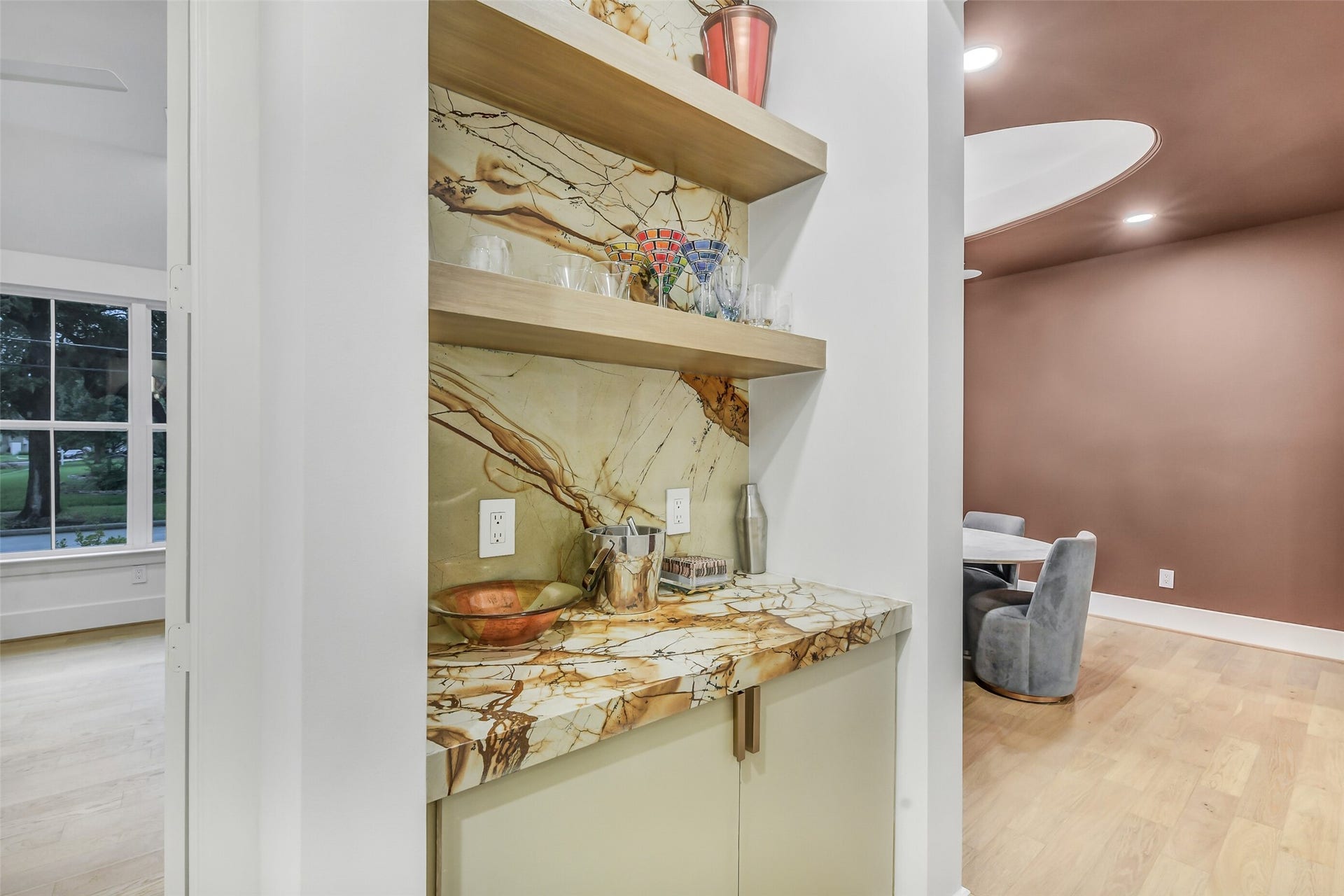 9411 Millbury Drive, Houston, TX 77096 Tucked between the kitchen and dining room, this chic dry bar features open wood shelving and a striking stone slab backsplash, offering both storage and style for effortless entertaining.