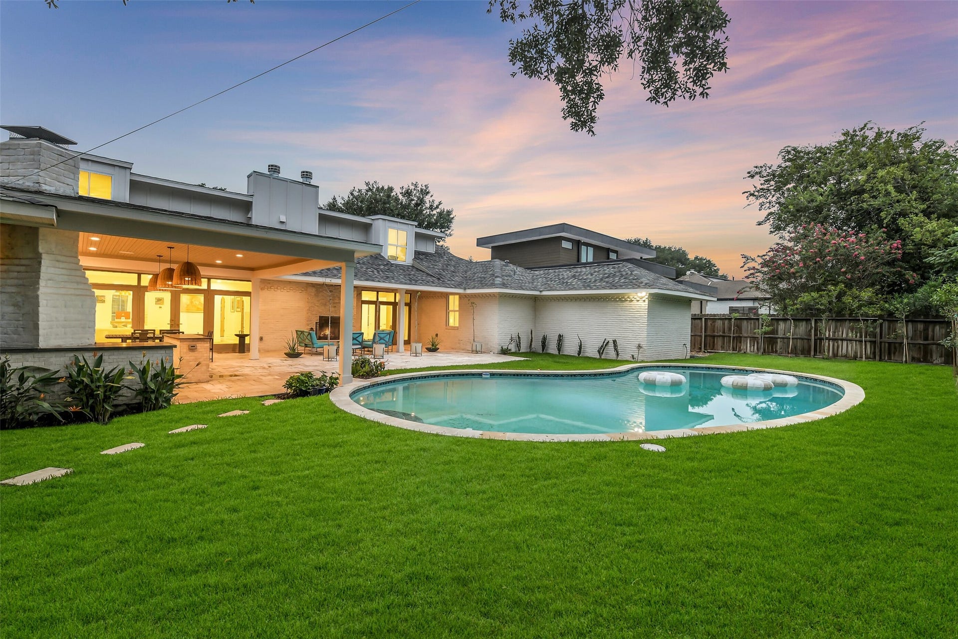9411 Millbury Drive, Houston, TX 77096 Sleek modern exterior, sparkling pool, and expansive lawn. Mature trees provide privacy on all sides, framing this beautifully designed outdoor retreat.