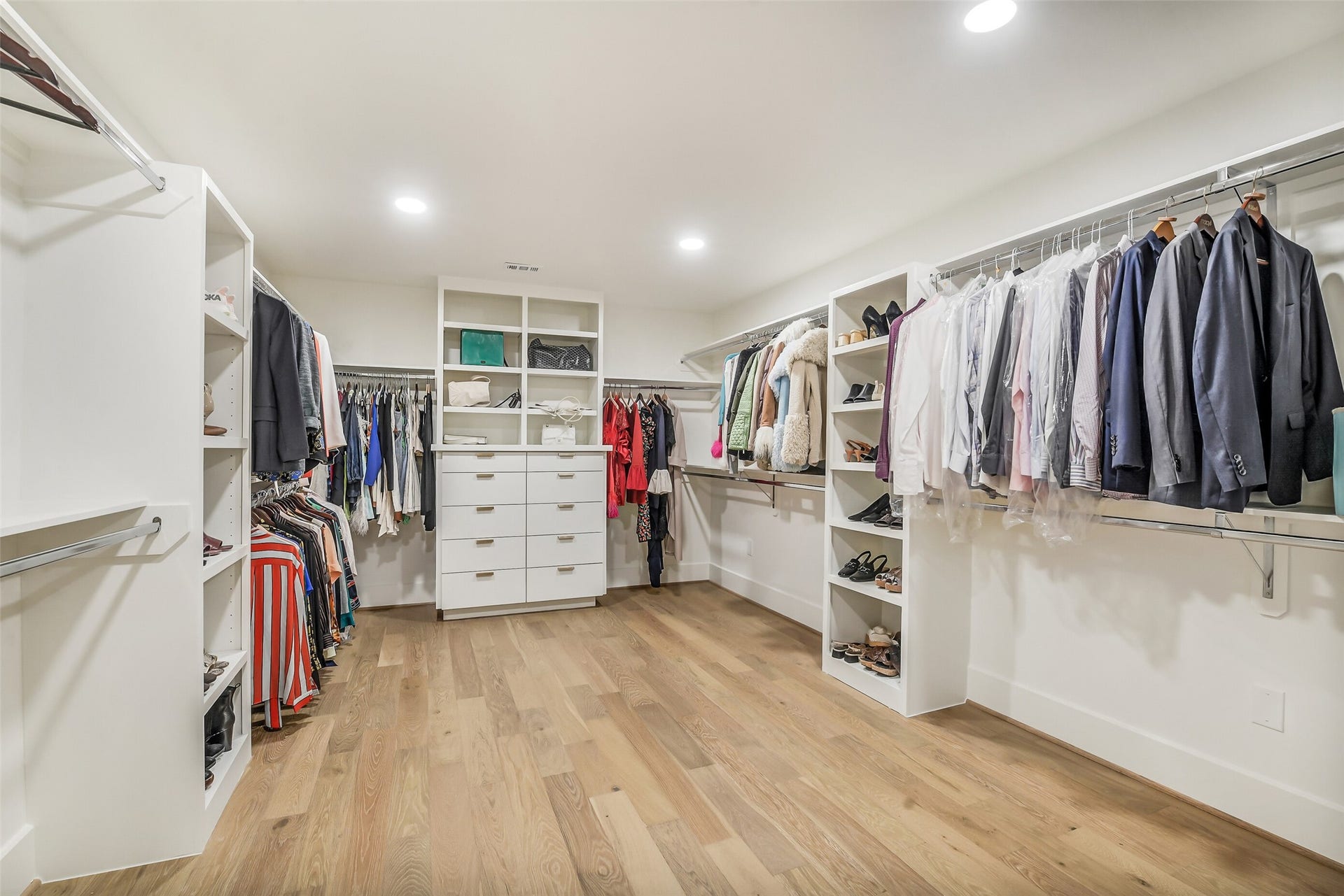 9411 Millbury Drive, Houston, TX 77096 A massive walk-in closet outfitted with custom built-ins, ample hanging space, and a center island of drawers for organized storage. Shoe shelving, open cubbies, and a spacious layout make this a true dream closet.