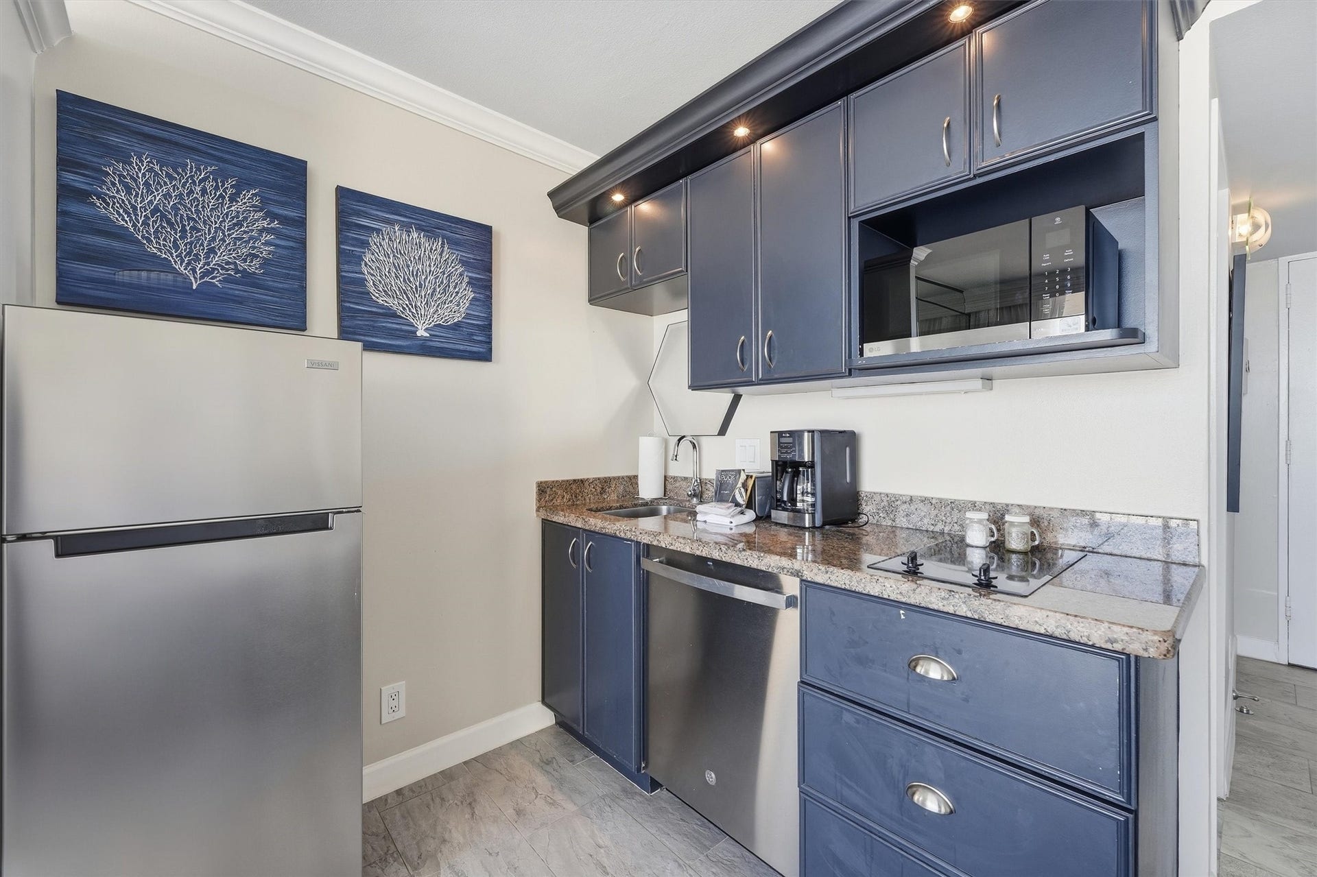 5220 Seawall Boulevard, #1038D, Galveston, TX 77551 The kitchenette features navy cabinetry, a stainless steel refrigerator, microwave, and dishwasher.