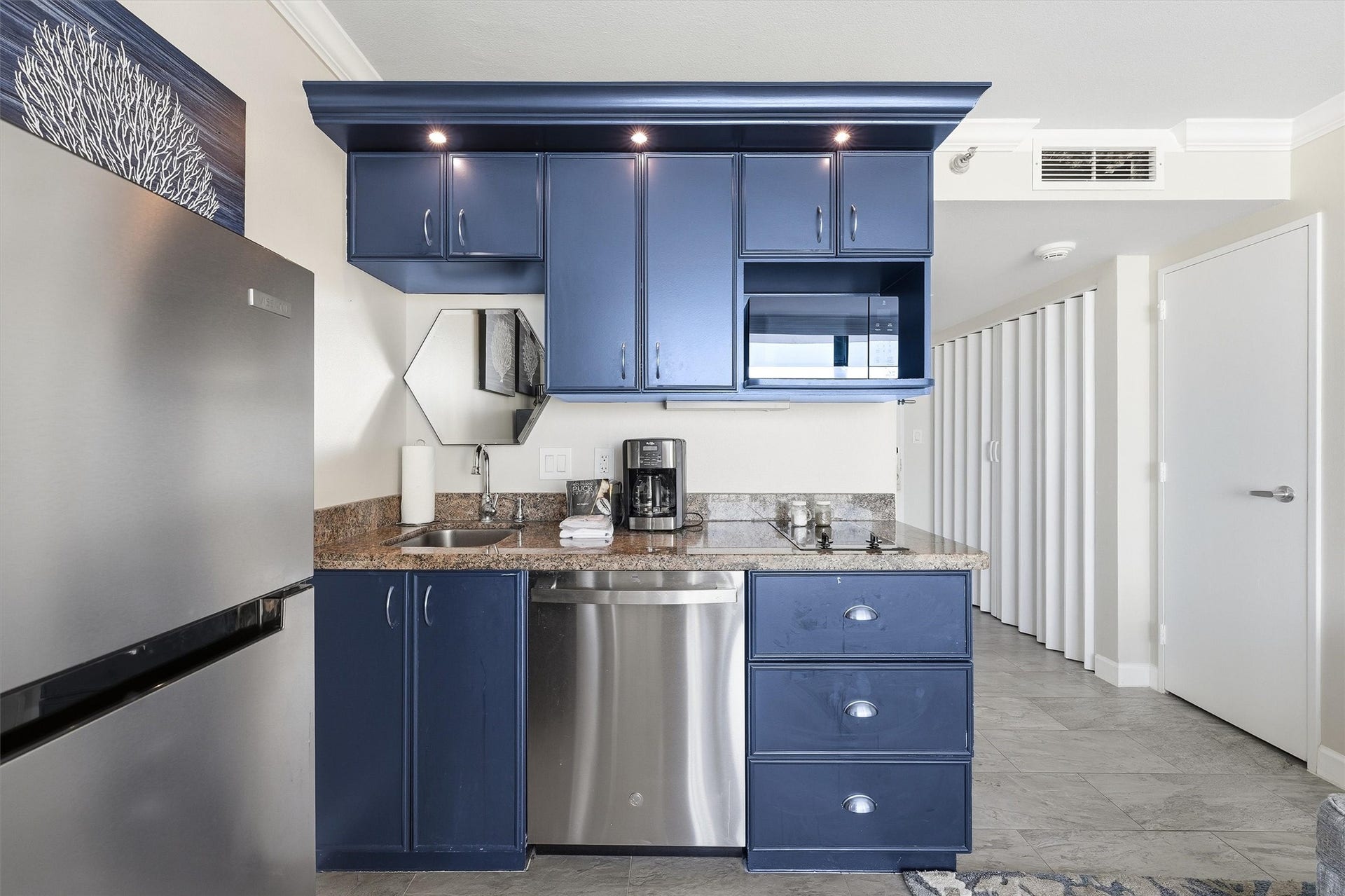 5220 Seawall Boulevard, #1038D, Galveston, TX 77551 Coordinating countertops, cabinet lighting, and a mirrored backsplash complement the coastal blue cabinetry.
