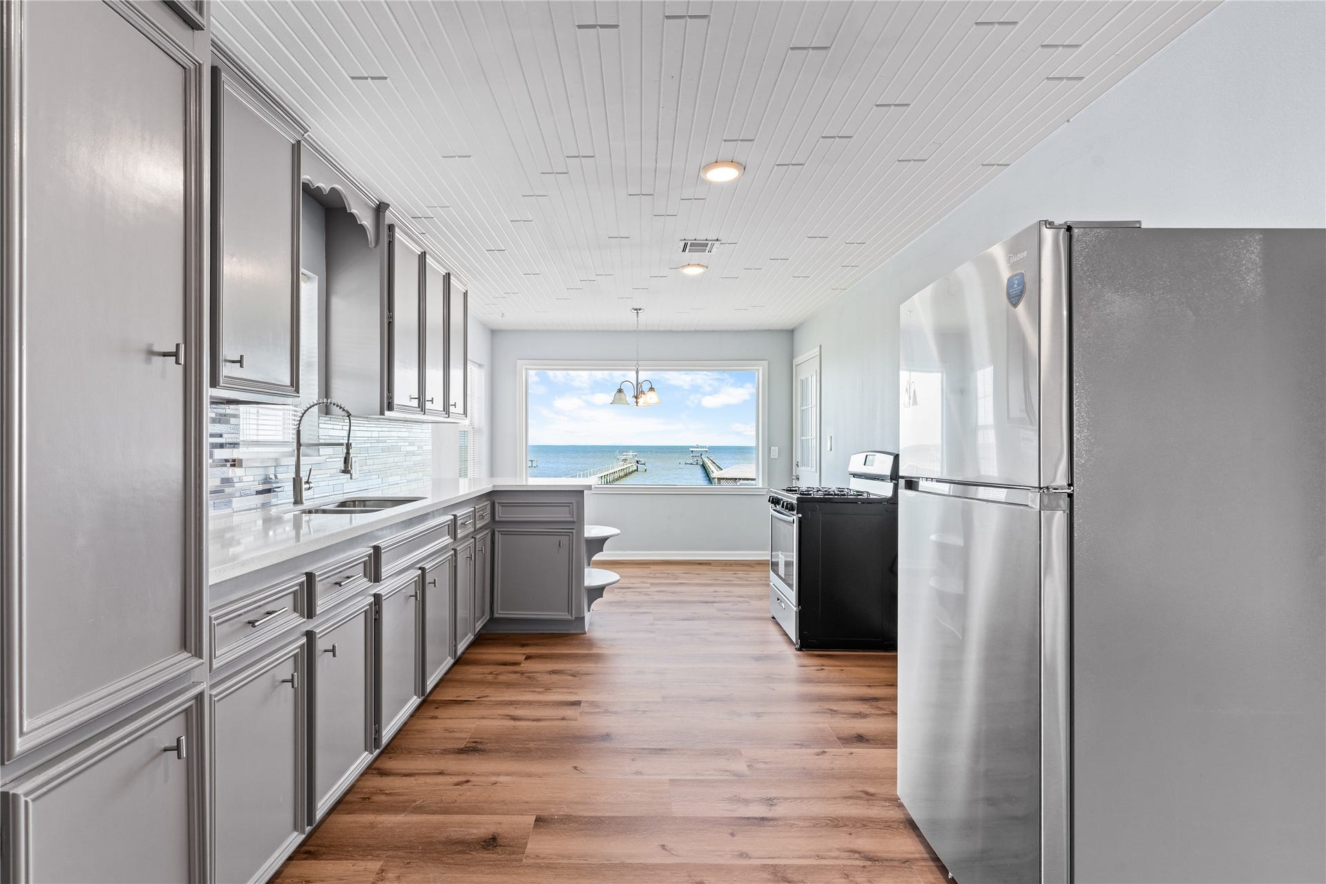 645 3rd Street, San Leon, TX 77539 The eye naturally moves from tailored cabinetry and quartz surfaces to the expansive bay beyond, creating a kitchen that feels both grounded and effortlessly connected to its surroundings.