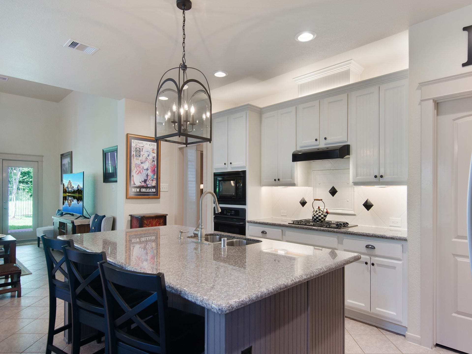 Notice the designer lantern-style light fixture and the contrasting island finish, thoughtful details that enhance the kitchen's transitional design and visual appeal.