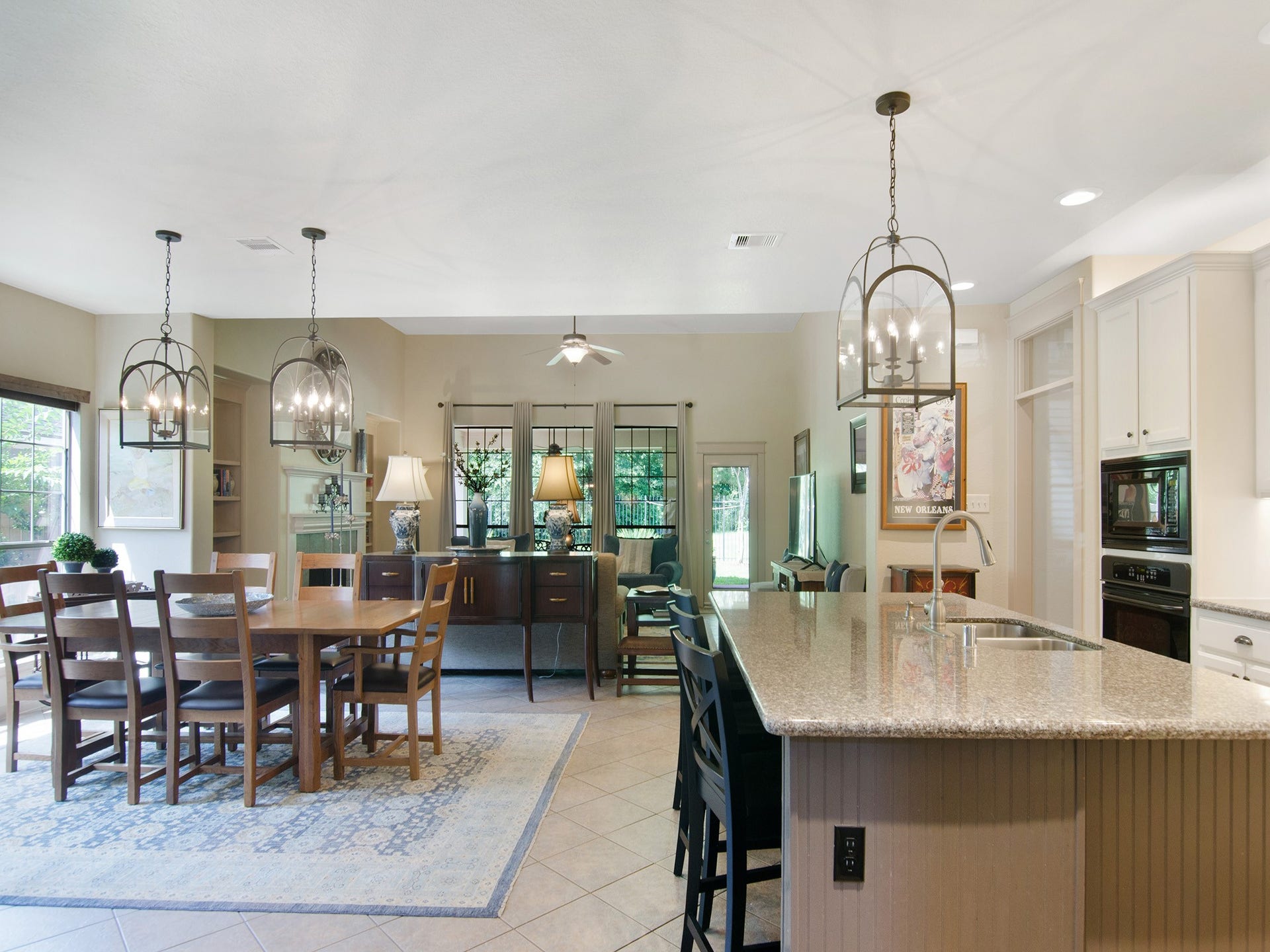 This spacious casual dining area seamlessly connects the kitchen and family room, while coordinating designer light fixtures blend the rooms together and enhance the home's cohesive design.