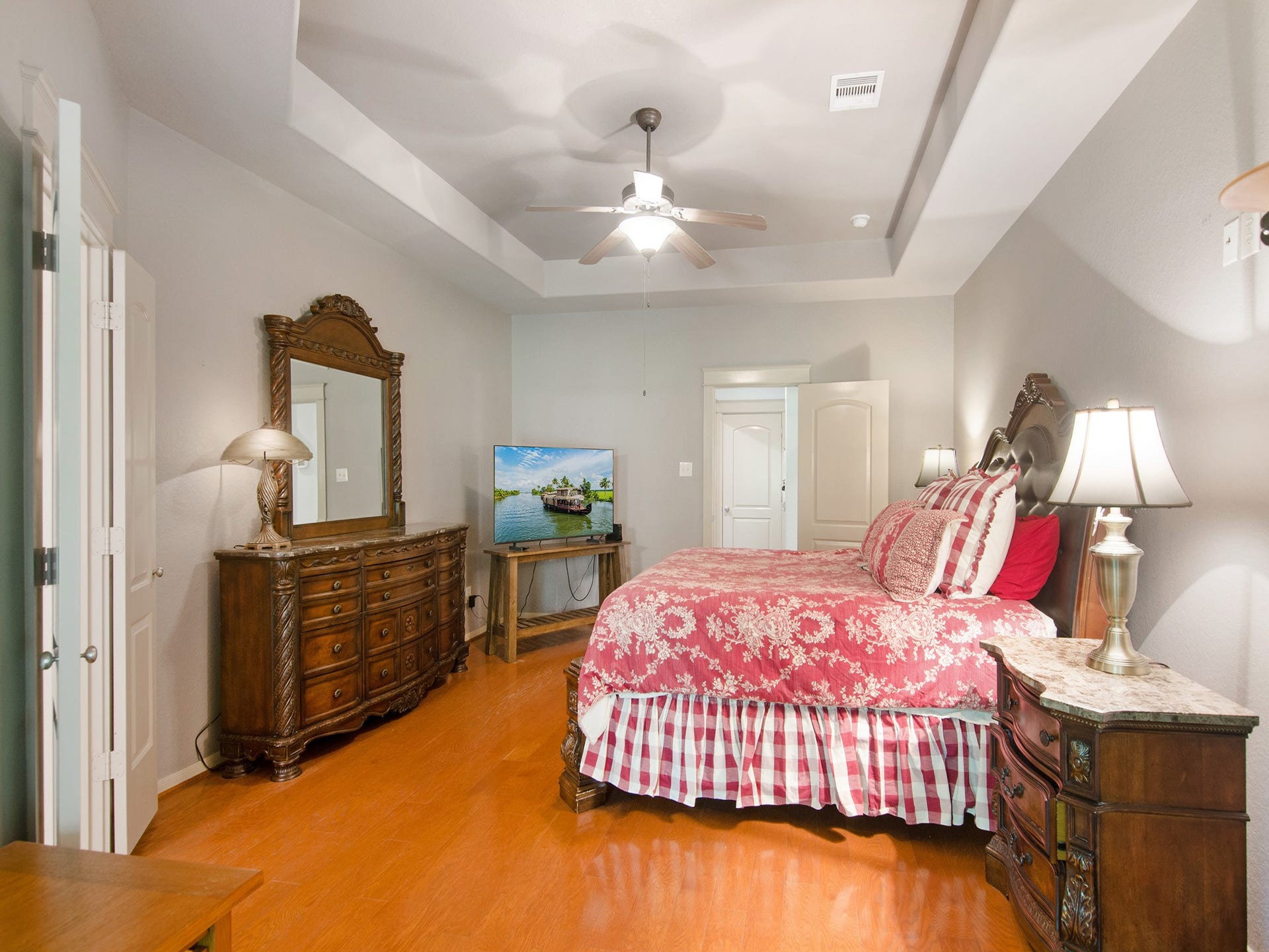 The spacious primary suite easily accommodates large-scale furniture and features warm wood flooring and an attractive trey ceiling.