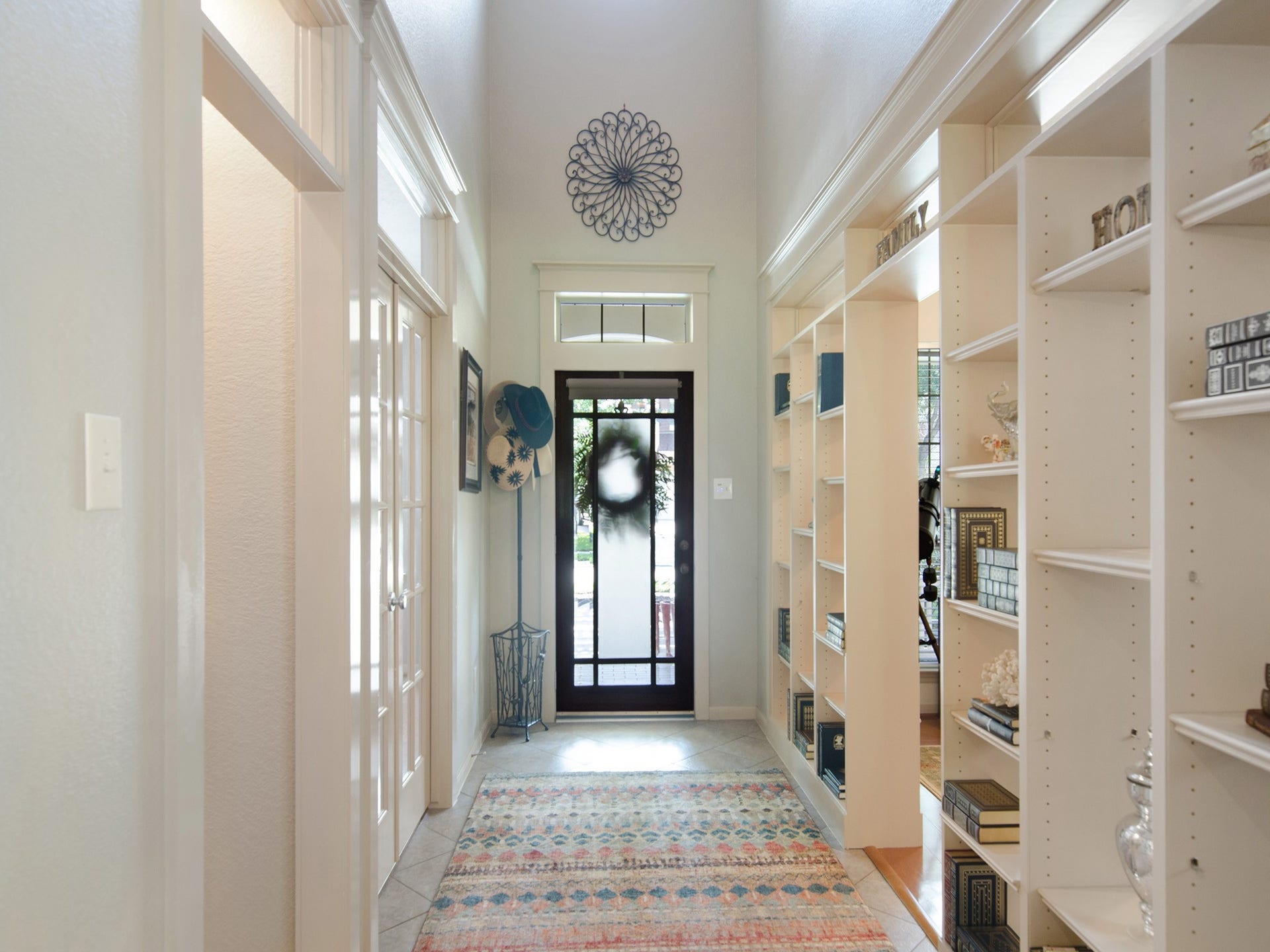 A soaring two-story entry makes a stunning first impression, featuring custom built-in bookshelves that create a distinctive home office space. French doors open to the formal dining room, while the natural light and thoughtful architectural details add warmth and character throughout the home.