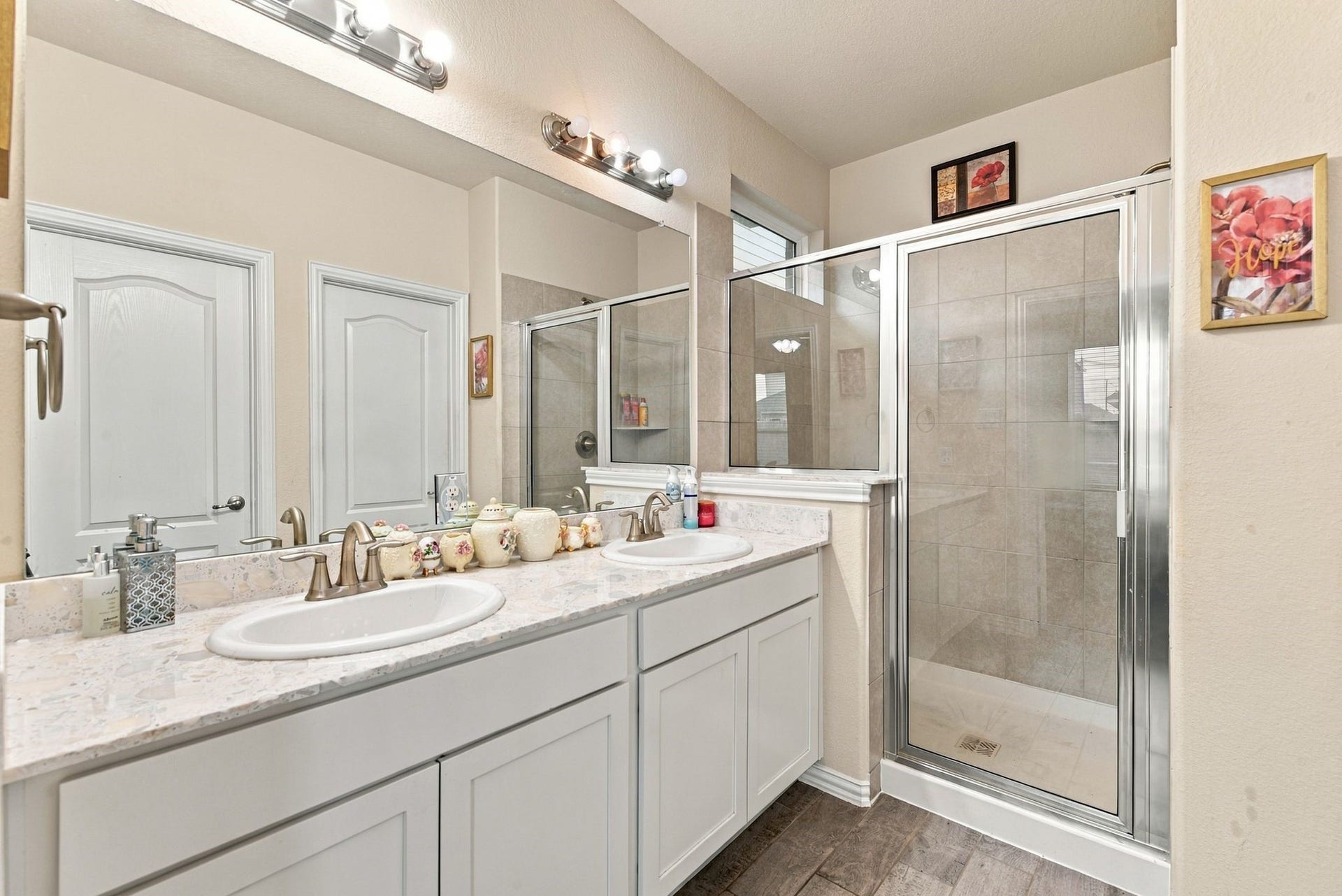 13202 Dancing Reed Drive, Texas City, TX 77568 Ensuite bathroom featuring a dual-sink vanity with modern fixtures, complemented by a spacious glass-enclosed shower and tasteful tile accents.