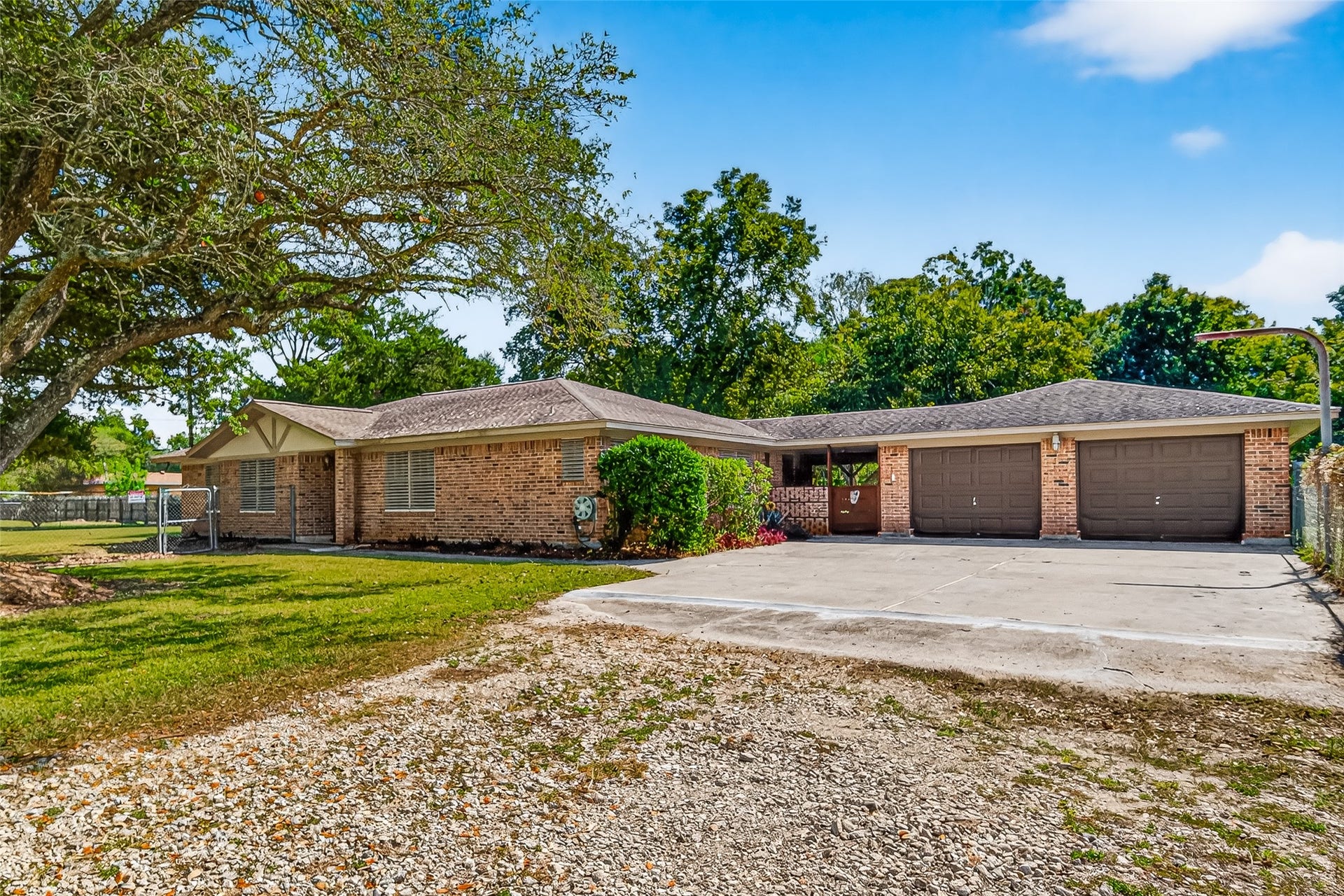 12021 7th 1/2 Street, Santa Fe, TX 77510 This is a spacious, single-story brick home with a three-car garage and a large driveway. The property features a well-maintained lawn with mature trees, offering a serene and private setting.