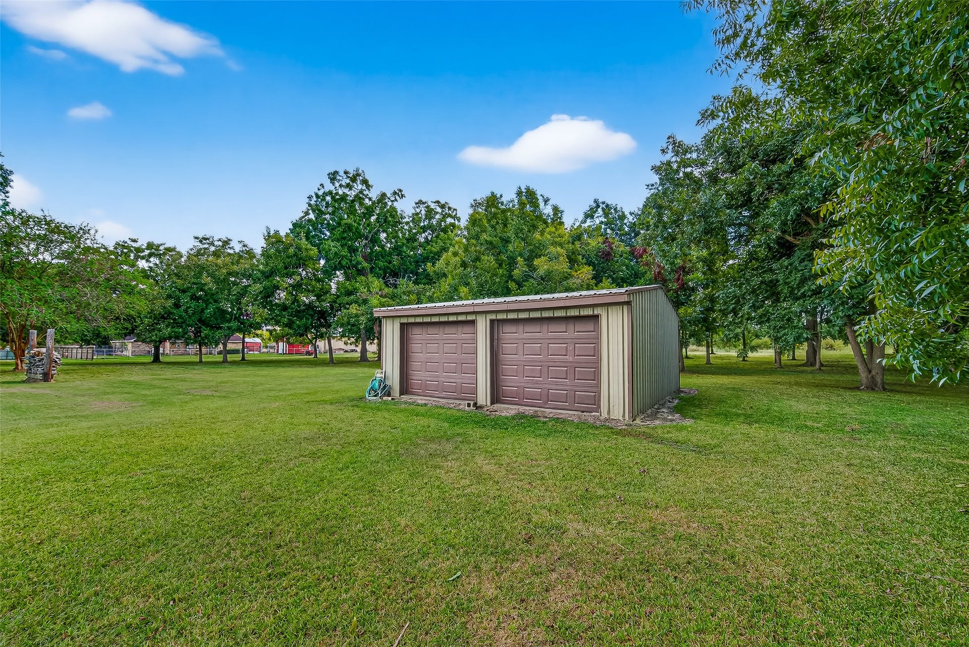 12021 7th 1/2 Street, Santa Fe, TX 77510 This photo shows a spacious backyard featuring a workshop for enthusiast or side business, surrounded by lush green grass and mature trees, providing a serene and private setting.
