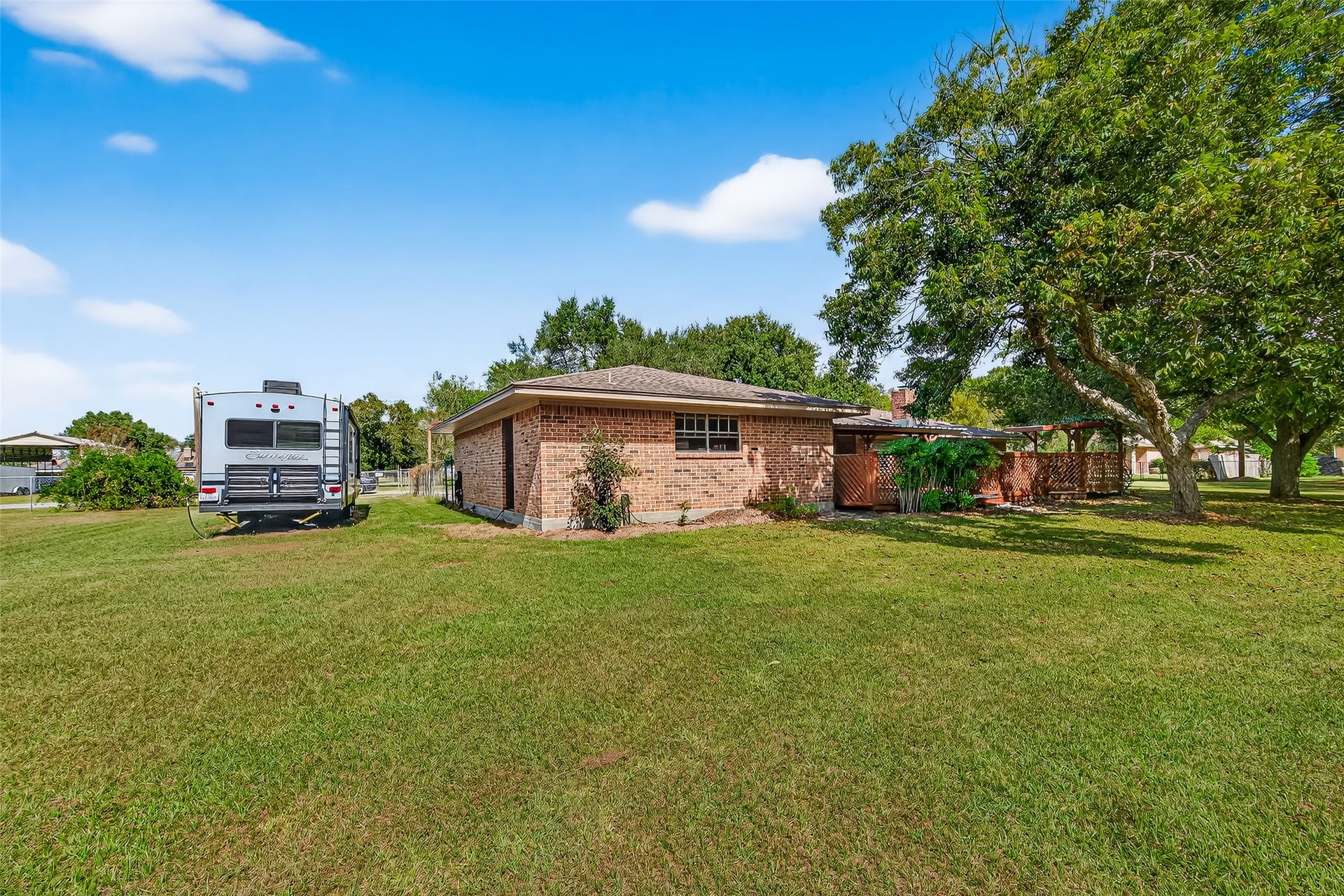 12021 7th 1/2 Street, Santa Fe, TX 77510 This photo shows a single-story brick house with a spacious backyard. There's a large grassy area and the property has a cozy, private feel with a covered patio area. Ideal for outdoor enthusiasts seeking ample space.
