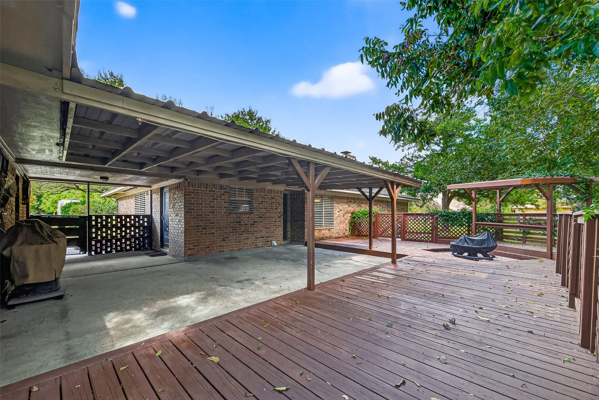 12021 7th 1/2 Street, Santa Fe, TX 77510 Spacious backyard with a large wooden deck and covered patio area. Ideal for outdoor entertaining and relaxing, surrounded by mature trees for added privacy.
