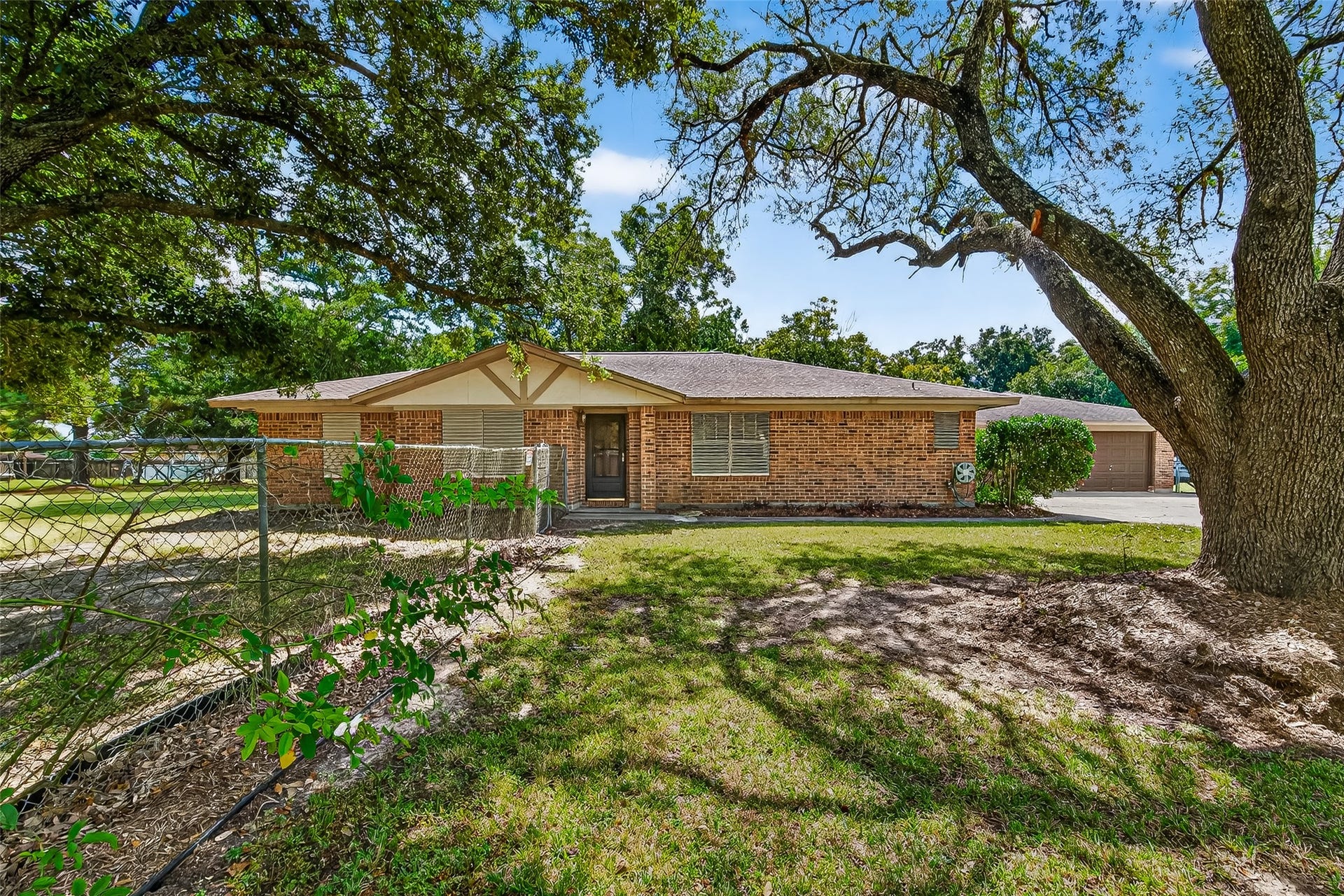 12021 7th 1/2 Street, Santa Fe, TX 77510 Charming brick ranch-style home with a welcoming front entrance, nestled among mature trees. The spacious yard offers shade and privacy, perfect for outdoor activities. Ideal for those seeking a serene and inviting environment.