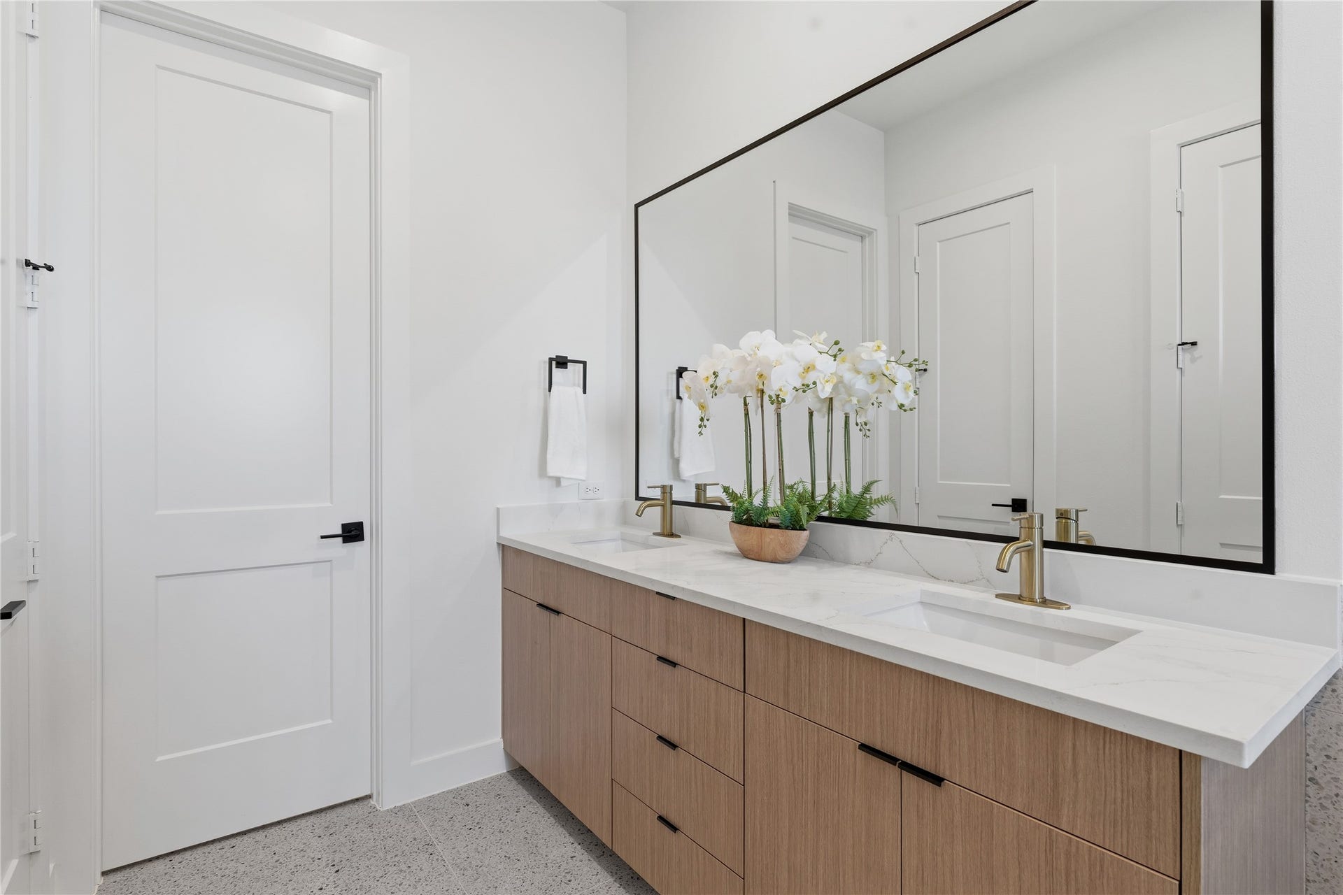 4610 Gunter Street, Houston, TX 77020 A double vanity with a light wood finish and white stone countertop anchors the bathroom. A large, black-framed mirror and brushed gold faucets provide sophisticated architectural accents.