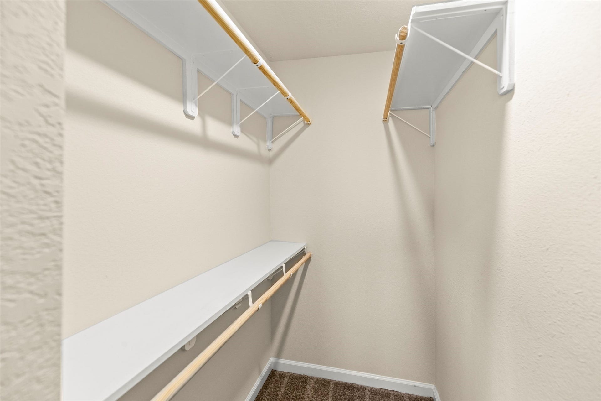 This photo showcases a walk-in closet with ample shelving and hanging space, featuring neutral walls and carpeting. Ideal for organized storage.