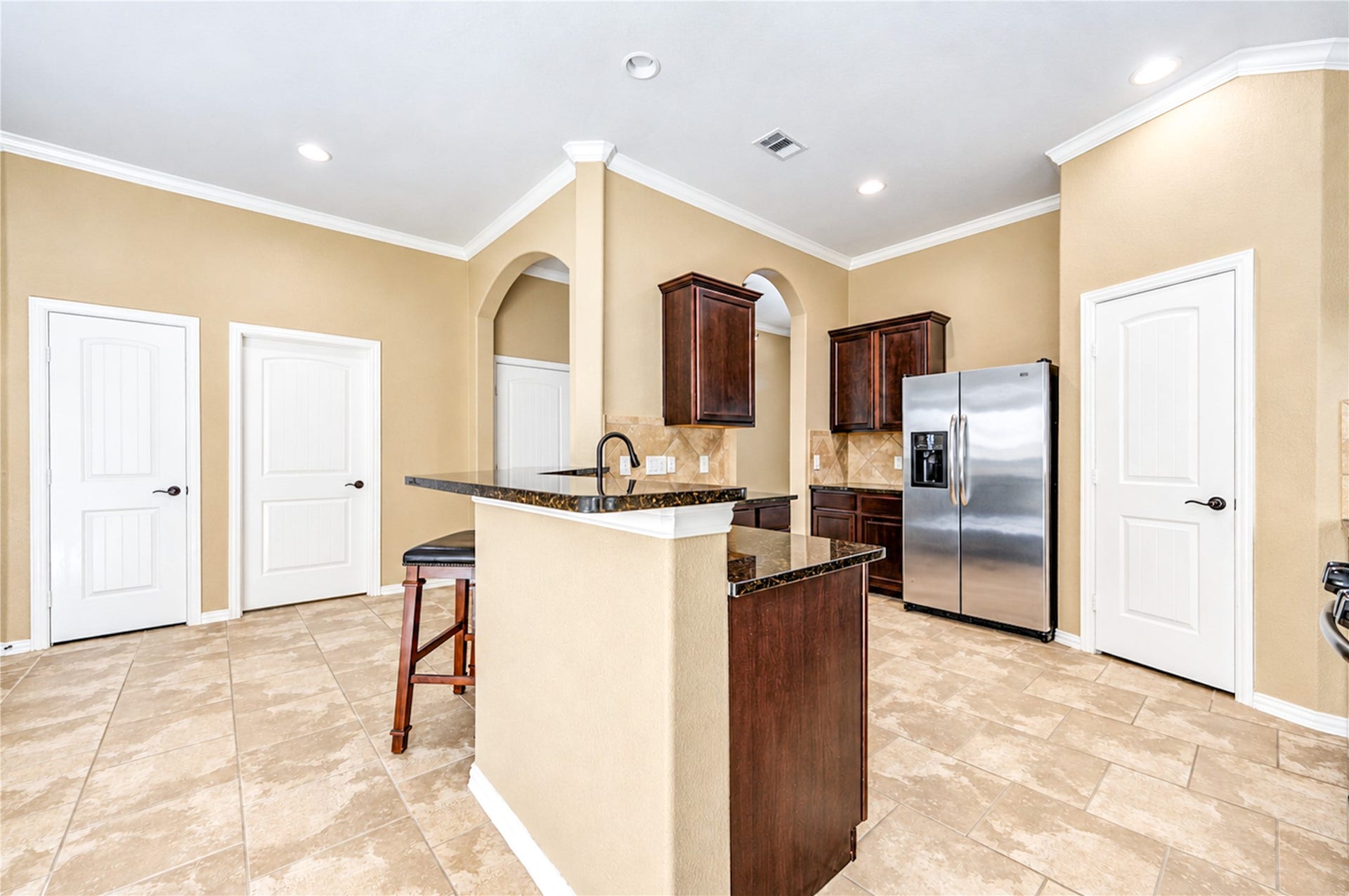 16719 Cactus Blossom Trail, Cypress, TX 77433 The kitchen island with its granite counter sits at the center of a bright, open plan with tile floors throughout.