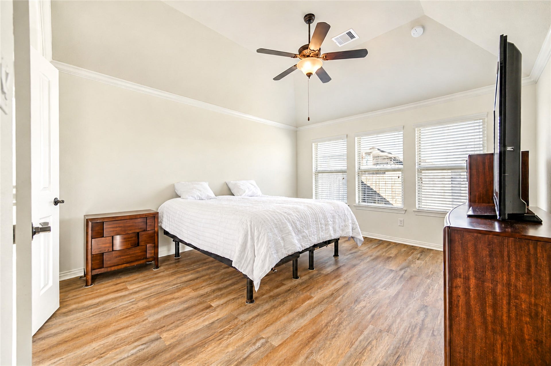 16719 Cactus Blossom Trail, Cypress, TX 77433 The primary bedroom has a vaulted ceiling, luxury vinyl plank flooring and a bank of windows.