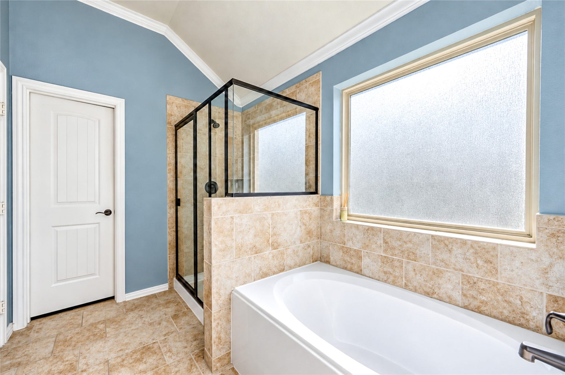 16719 Cactus Blossom Trail, Cypress, TX 77433 A soaking tub and glass-enclosed shower sit beneath a frosted window in the primary bath.
