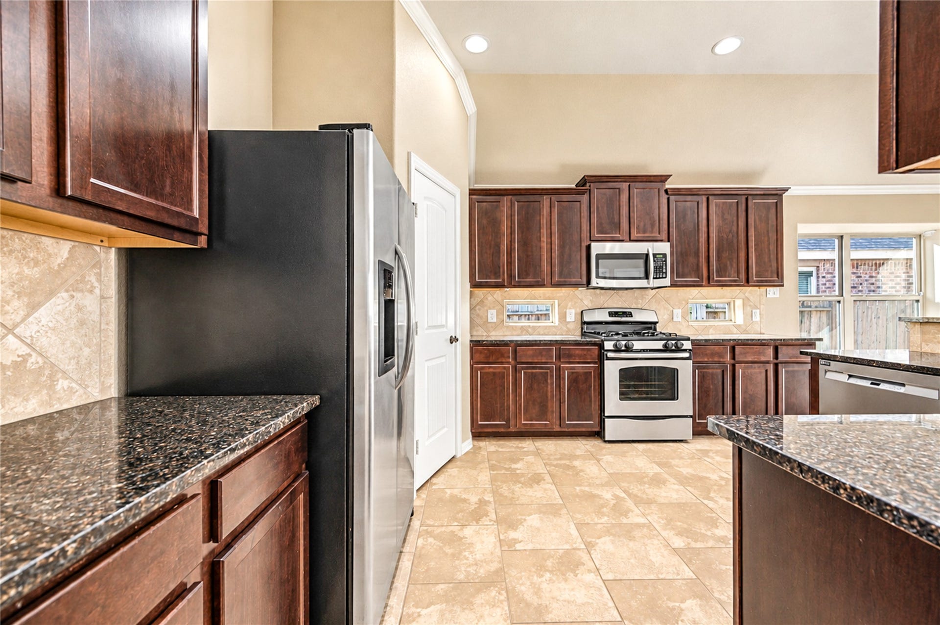 16719 Cactus Blossom Trail, Cypress, TX 77433 Dark wood cabinetry, granite counters and a gas range define the kitchen, with the pantry just beyond.