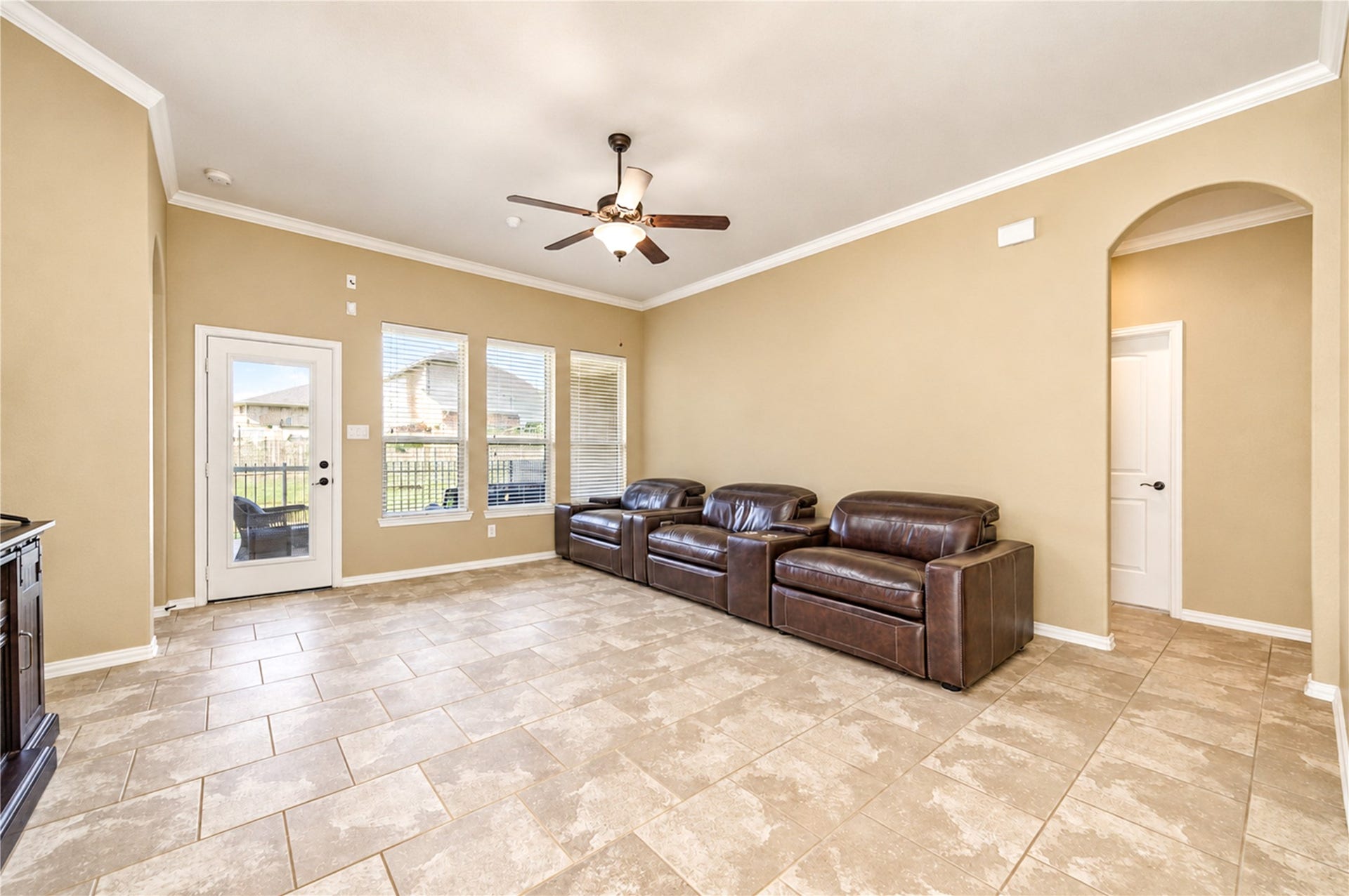 16719 Cactus Blossom Trail, Cypress, TX 77433 Tile floors and crown molding carry through the living room, with a door opening to the covered patio.