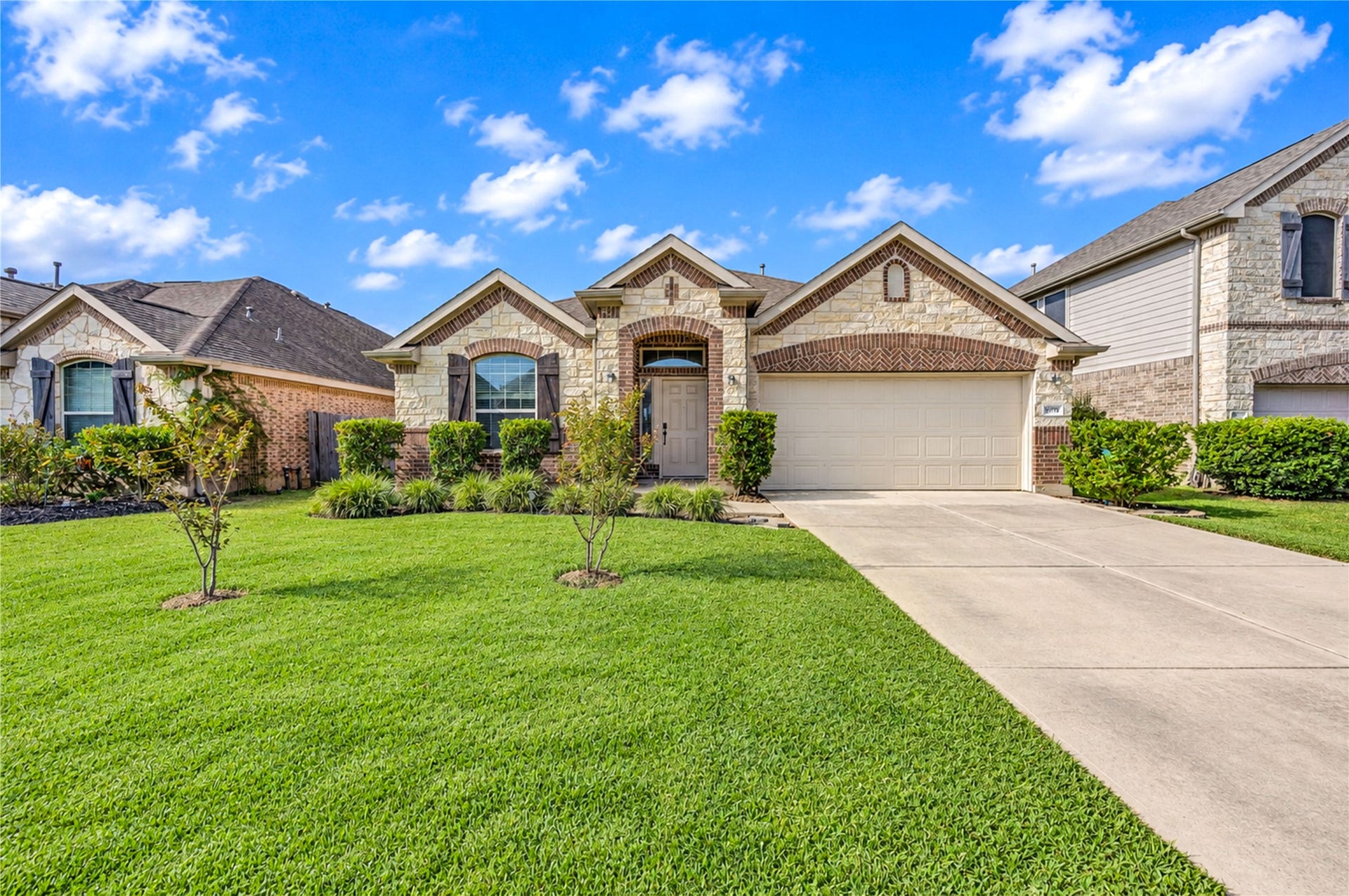 16719 Cactus Blossom Trail, Cypress, TX 77433 Brick and stone accents frame the arched entry beneath a layered roofline, with a lush front lawn leading to the drive.