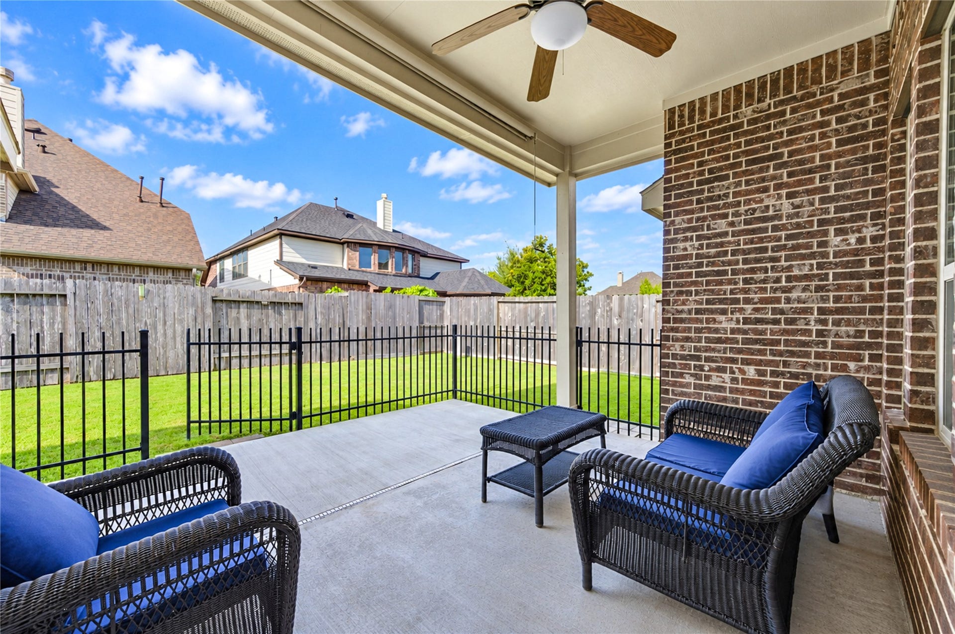 16719 Cactus Blossom Trail, Cypress, TX 77433 The covered patio extends the living space outdoors, with brick walls and a wrought-iron fence enclosing the yard.