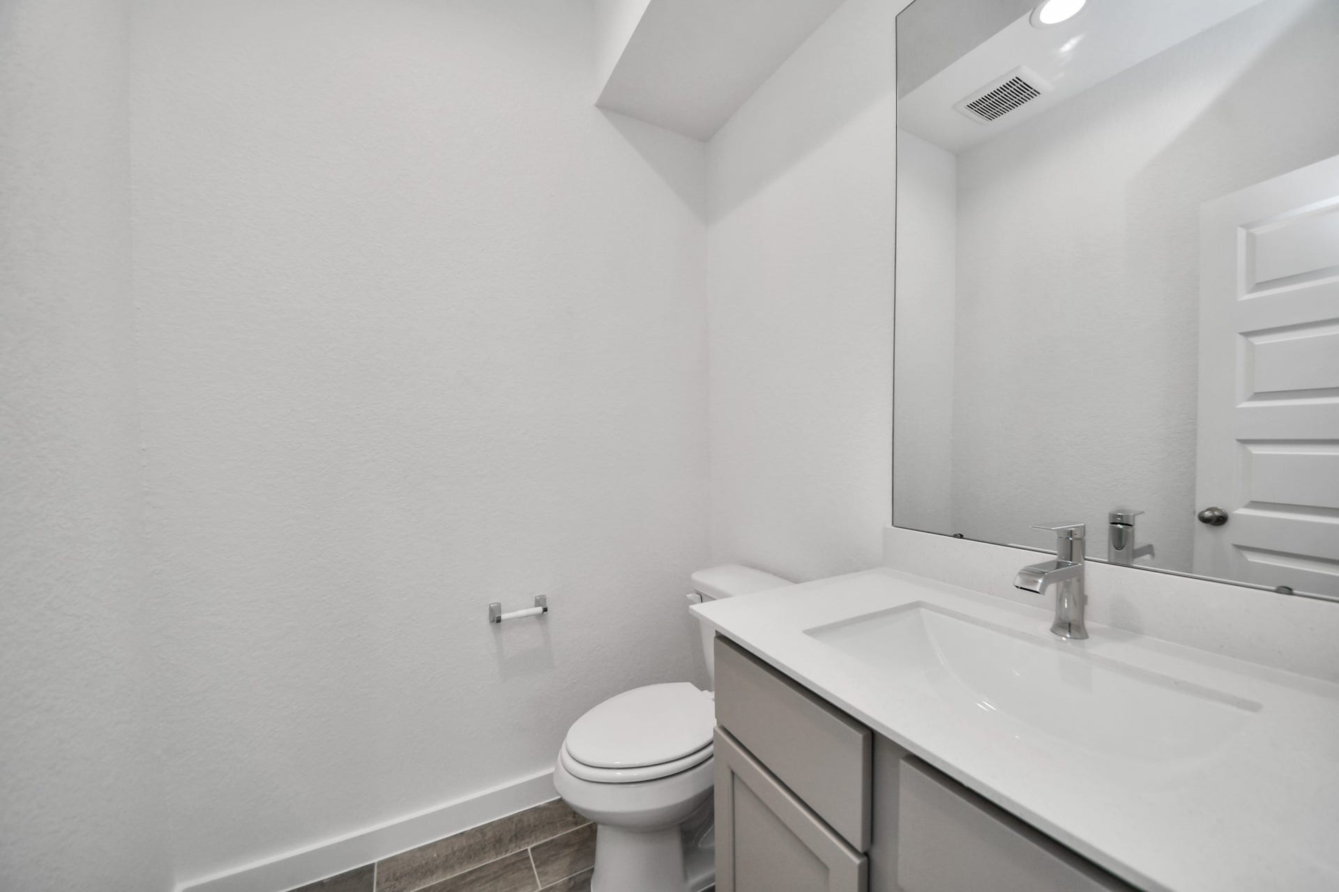 63 Knight Bayou Drive, Dayton, TX 77535 Sophisticated half bathroom adorned with contemporary finishes. The elegant 5-panel door welcomes you to a space where style meets functionality. Notice the sleek hardware accents that add a touch of modern charm. The vanity boasts light-colored countertops, beautifully complemented by a tasteful vanity light, creating a well-lit and inviting atmosphere. Sample photo of completed home with similar floor plan. Actual colors and selections may vary.