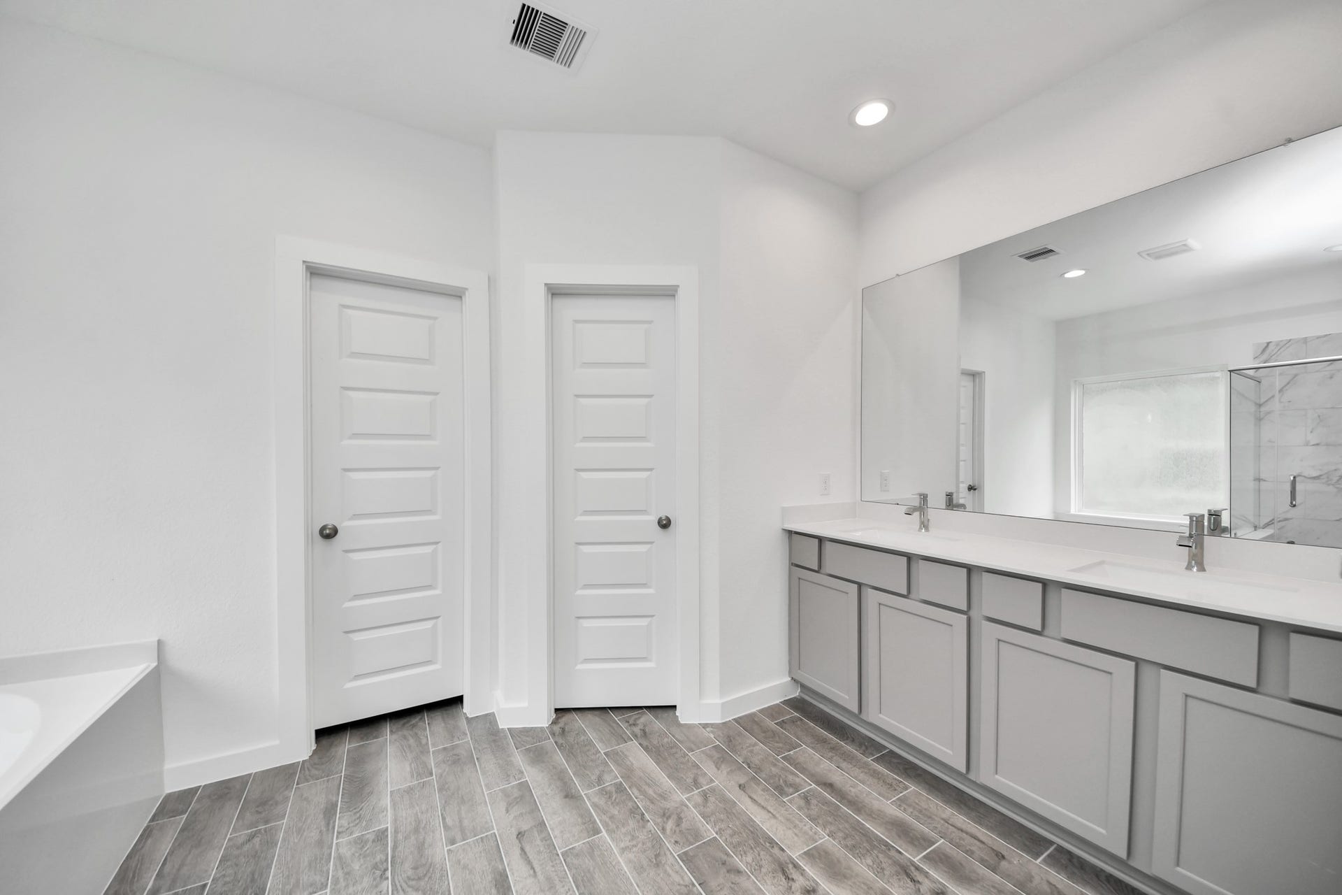 63 Knight Bayou Drive, Dayton, TX 77535 Escape to a spa-like oasis in this primary bathroom. Enjoy a walk-in shower with tile surround, a separate garden tub with custom detailing, and an elegant vanity featuring light countertops, modern hardware, and beautiful vanity lights. Experience luxury and relaxation in every detail. Sample photo of completed home with similar floor plan. Actual colors and selections may vary.