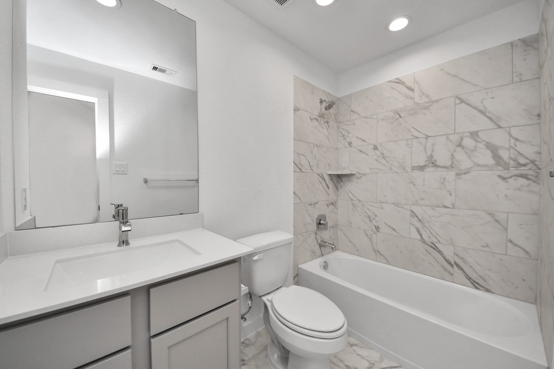 63 Knight Bayou Drive, Dayton, TX 77535 Secondary bath features tile flooring, bath/shower combo with tile surround, light stained wood cabinets, beautiful light countertop. Sample photo of completed home with similar floor plan. Actual colors and selections may vary.