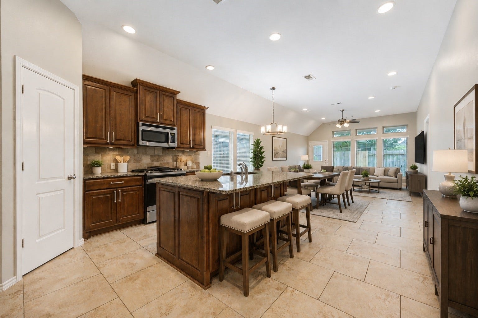 27407 Gatlin Lane, Spring, TX 77386 Kitchen boasts a large island and rich wood cabinetry opening to an adjoining living area; dining furniture shown is virtually staged. A functional layout built for everyday living.