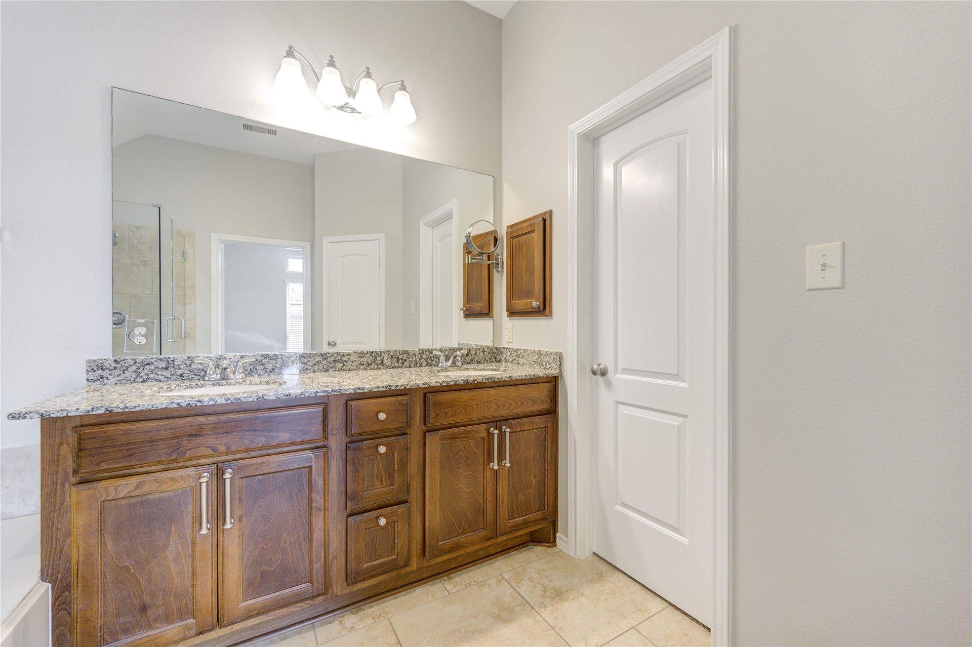 27407 Gatlin Lane, Spring, TX 77386 Sophisticated double-vanity bathroom with rich wood cabinetry and elegant mirrors. Style and function combined.