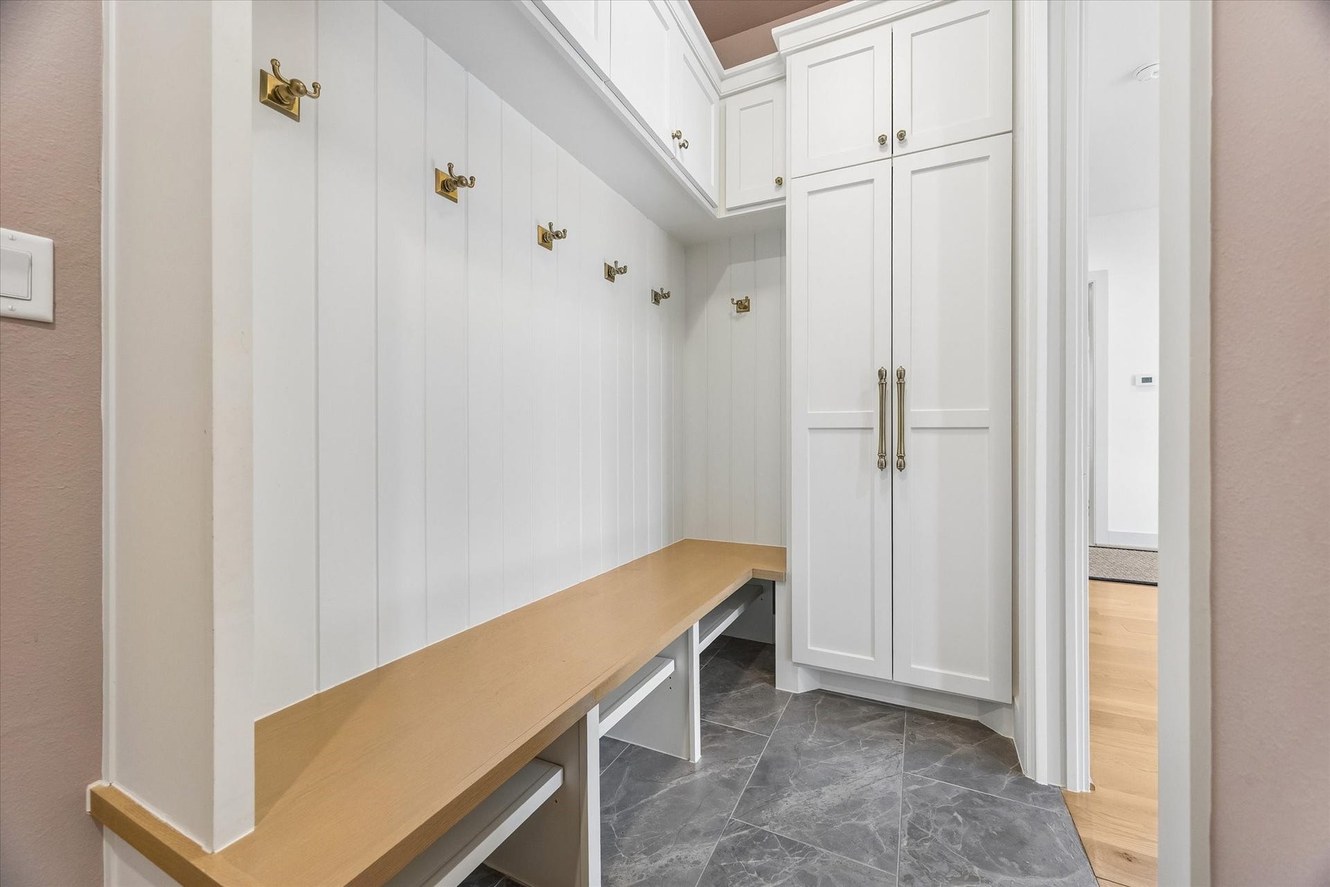 704 Teetshorn Street, Houston, TX 77009 Dedicated mudroom with a long built-in bench, brass hooks, paneled walls and extensive cabinetry for everyday storage.